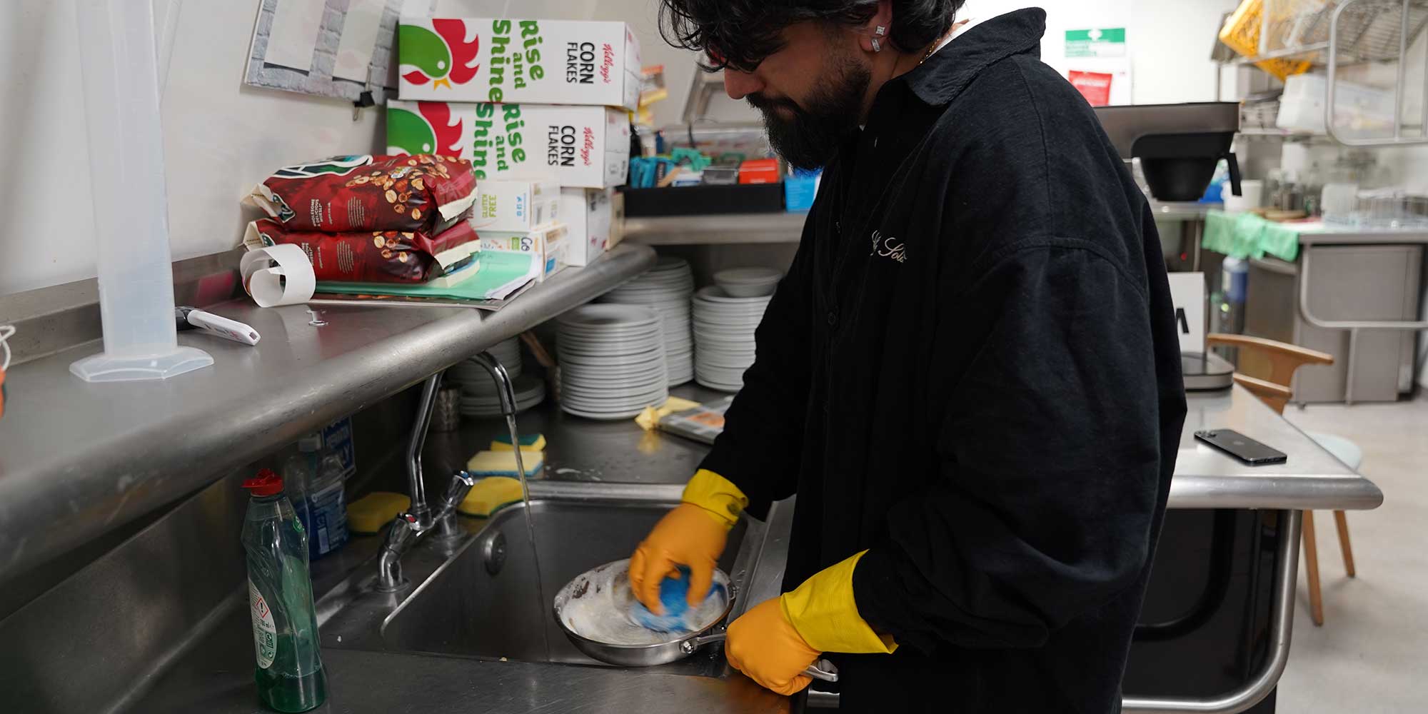 Our tester scrubbing dried scrambled eggs from a pan with a sponge.