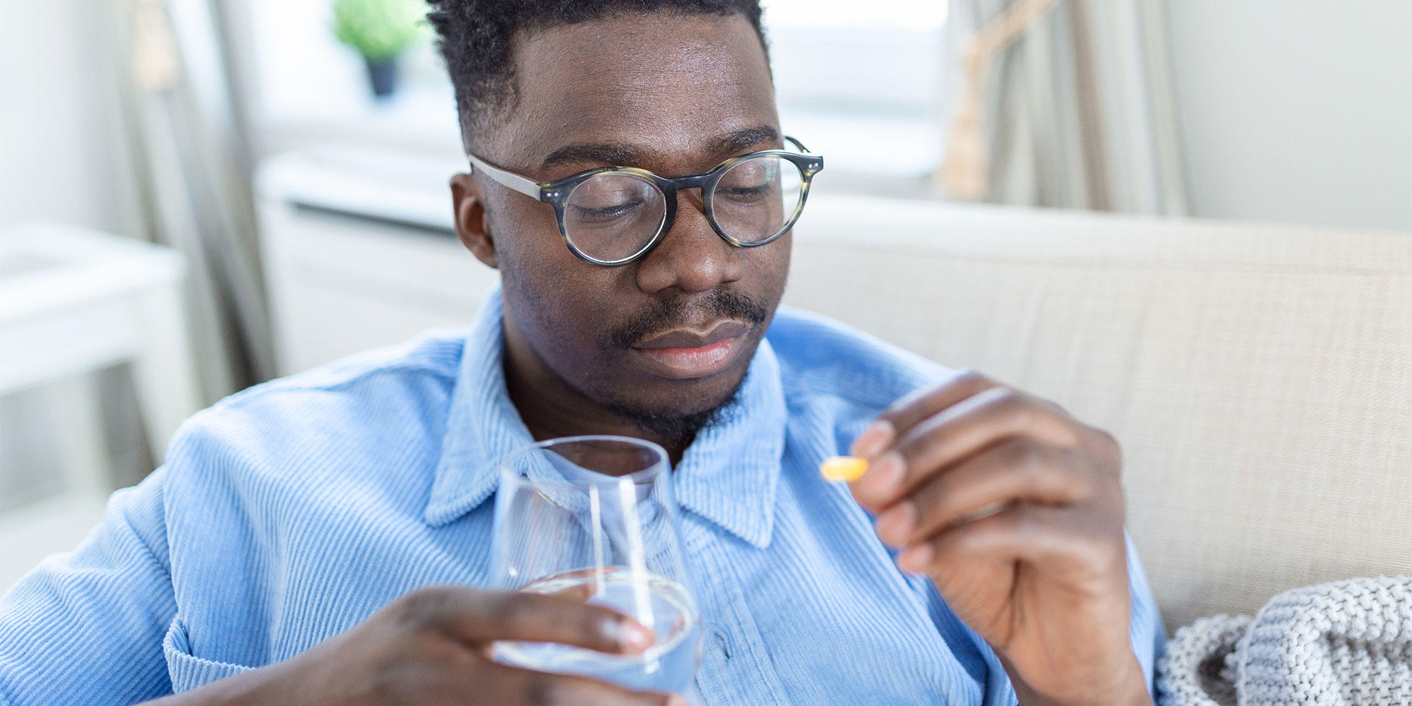 A man taking a supplement with water