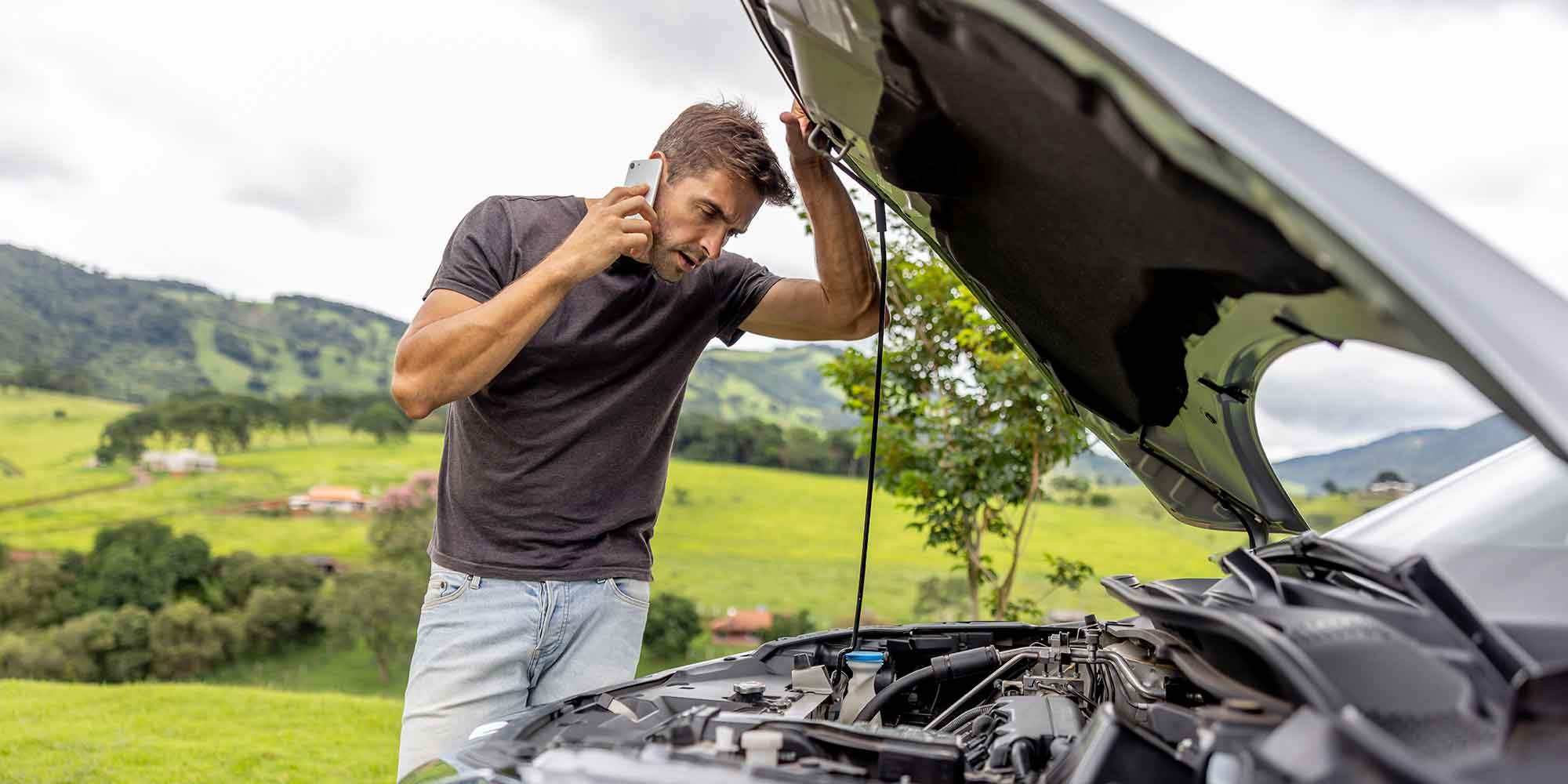 Car broken down with the bonnet open and driver looking at the engine