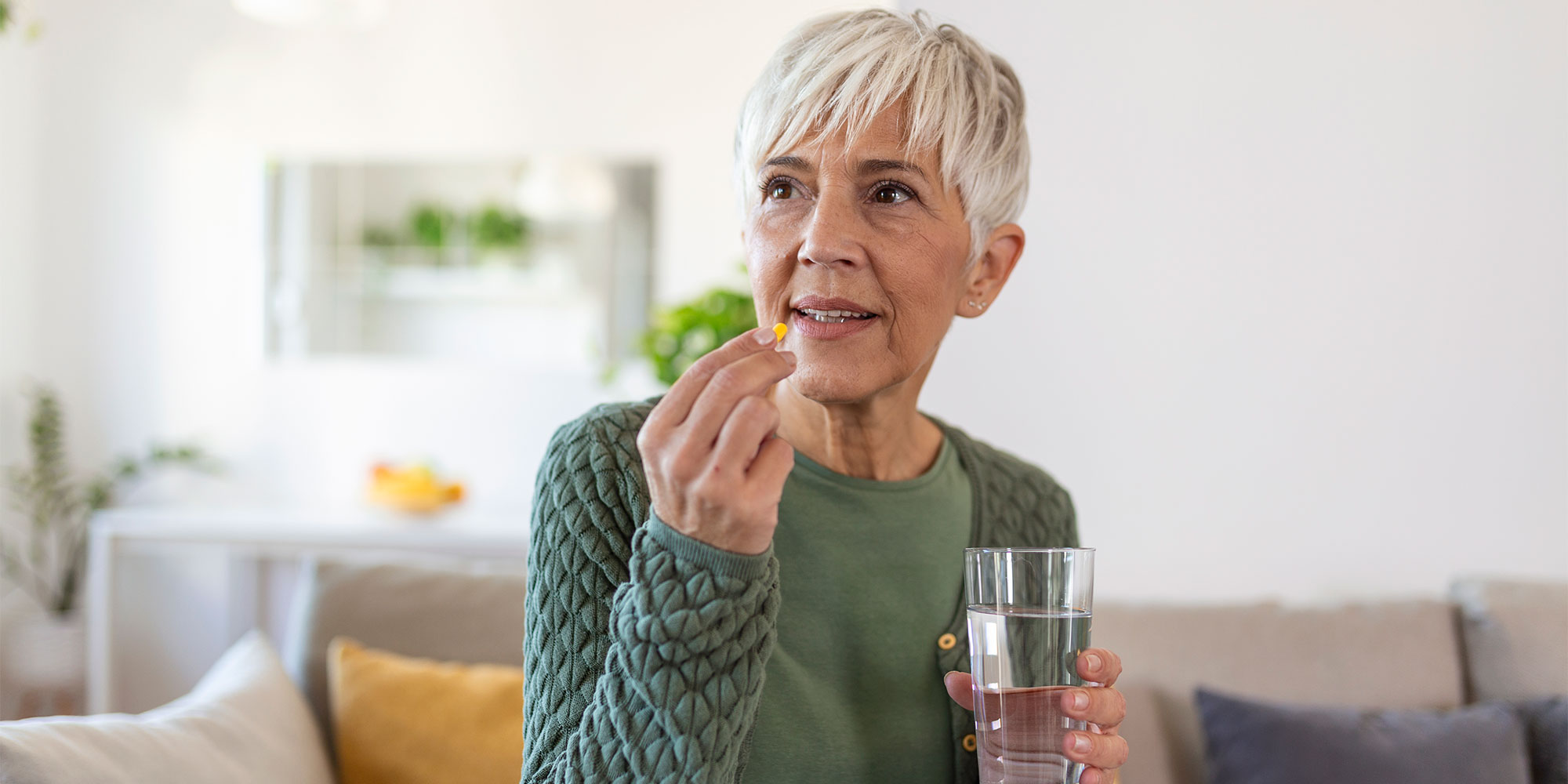 A woman taking a pill with a glass of water