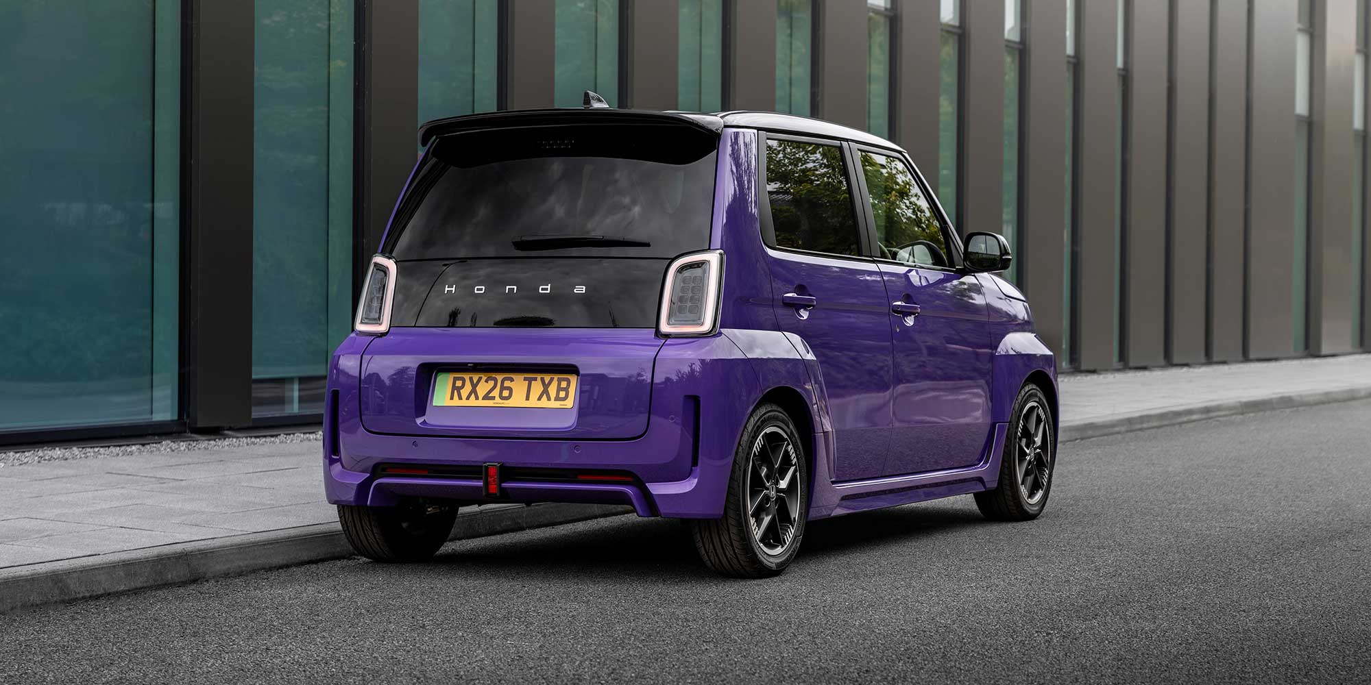 Rear view of a purple Honda Super-N car with license plate RX26 TXB parked on a street.
