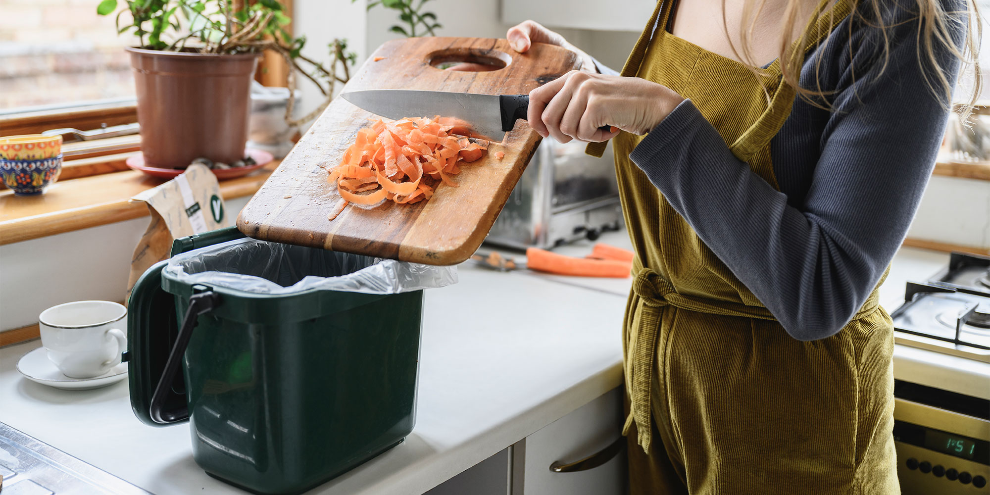Scraping carrot peel into a lined food waste caddy