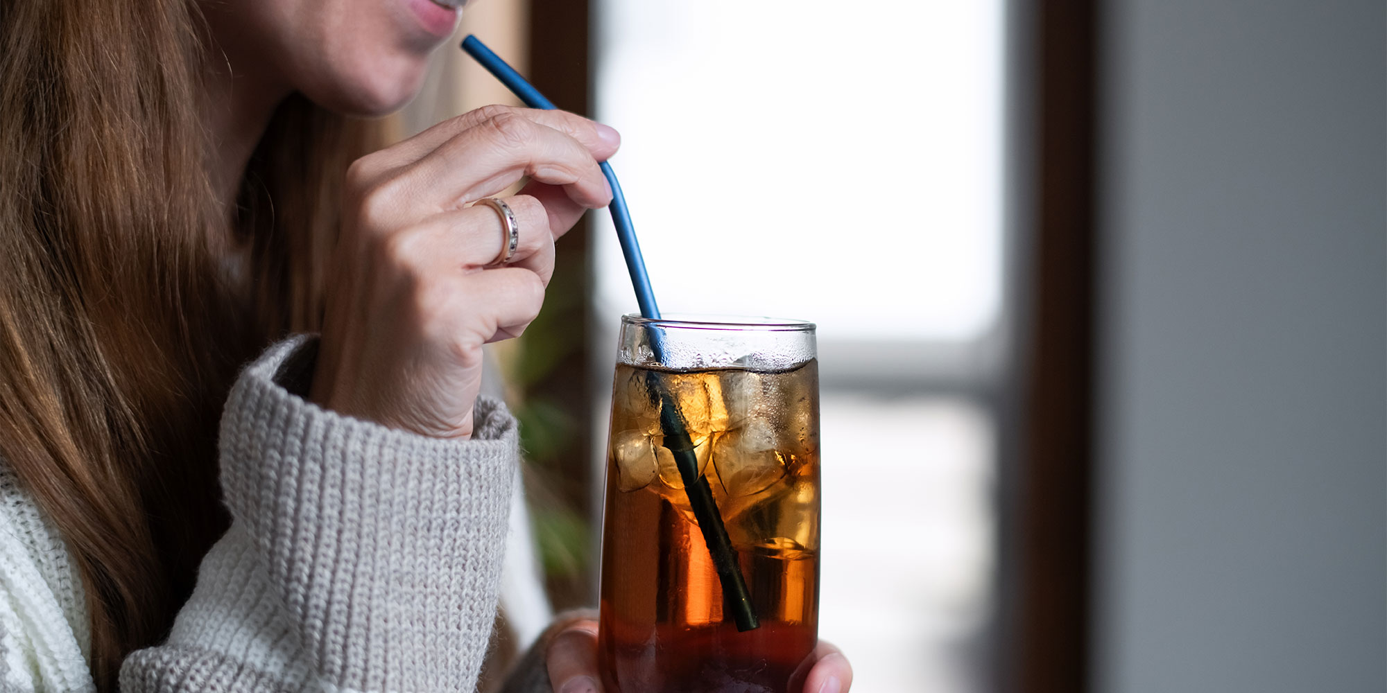A woman drinking a cola drink through a straw