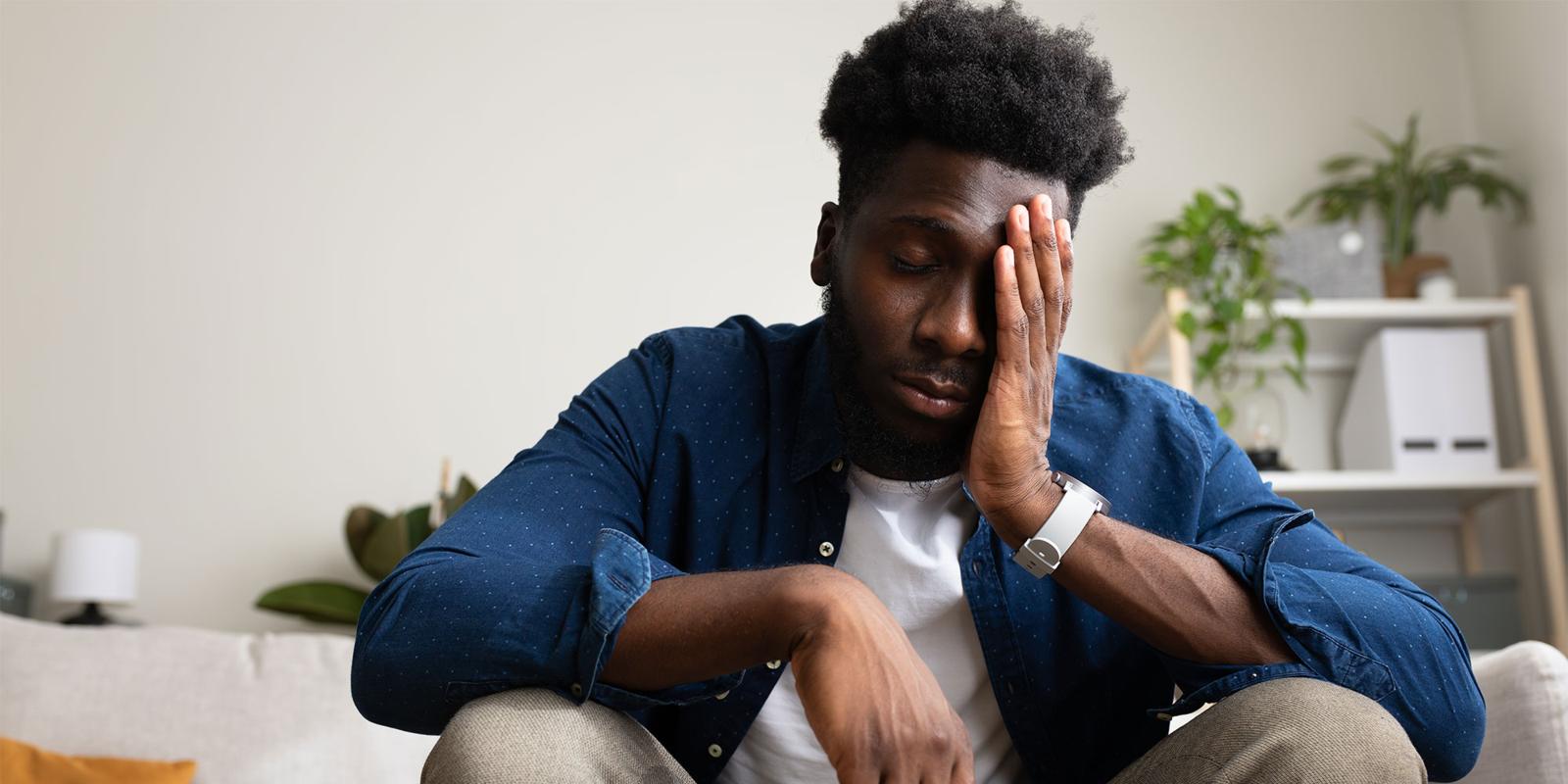 A man sitting on a sofa looking tired