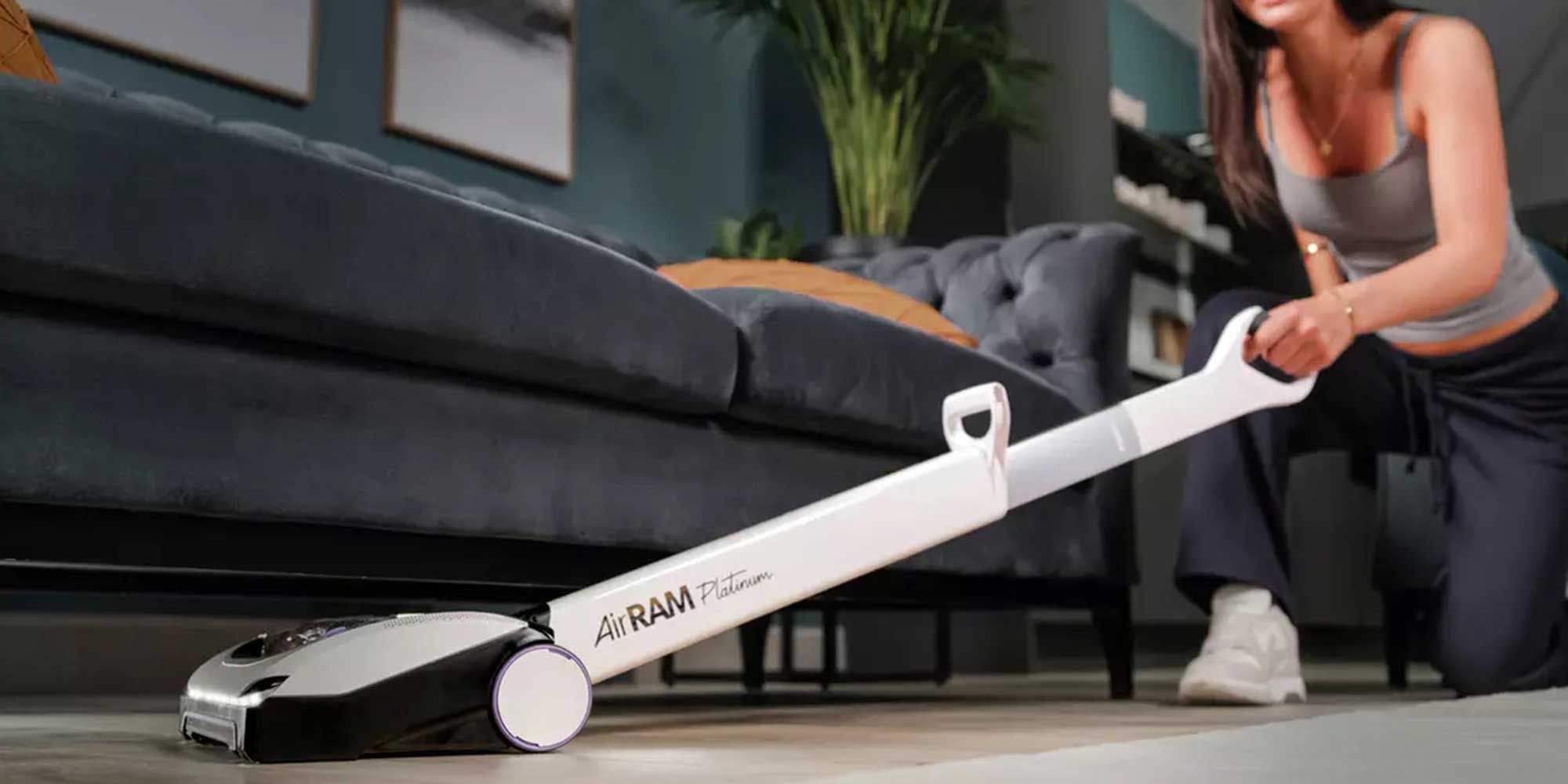 woman hoovering under the sofa with a gtech airram vacuum cleaner