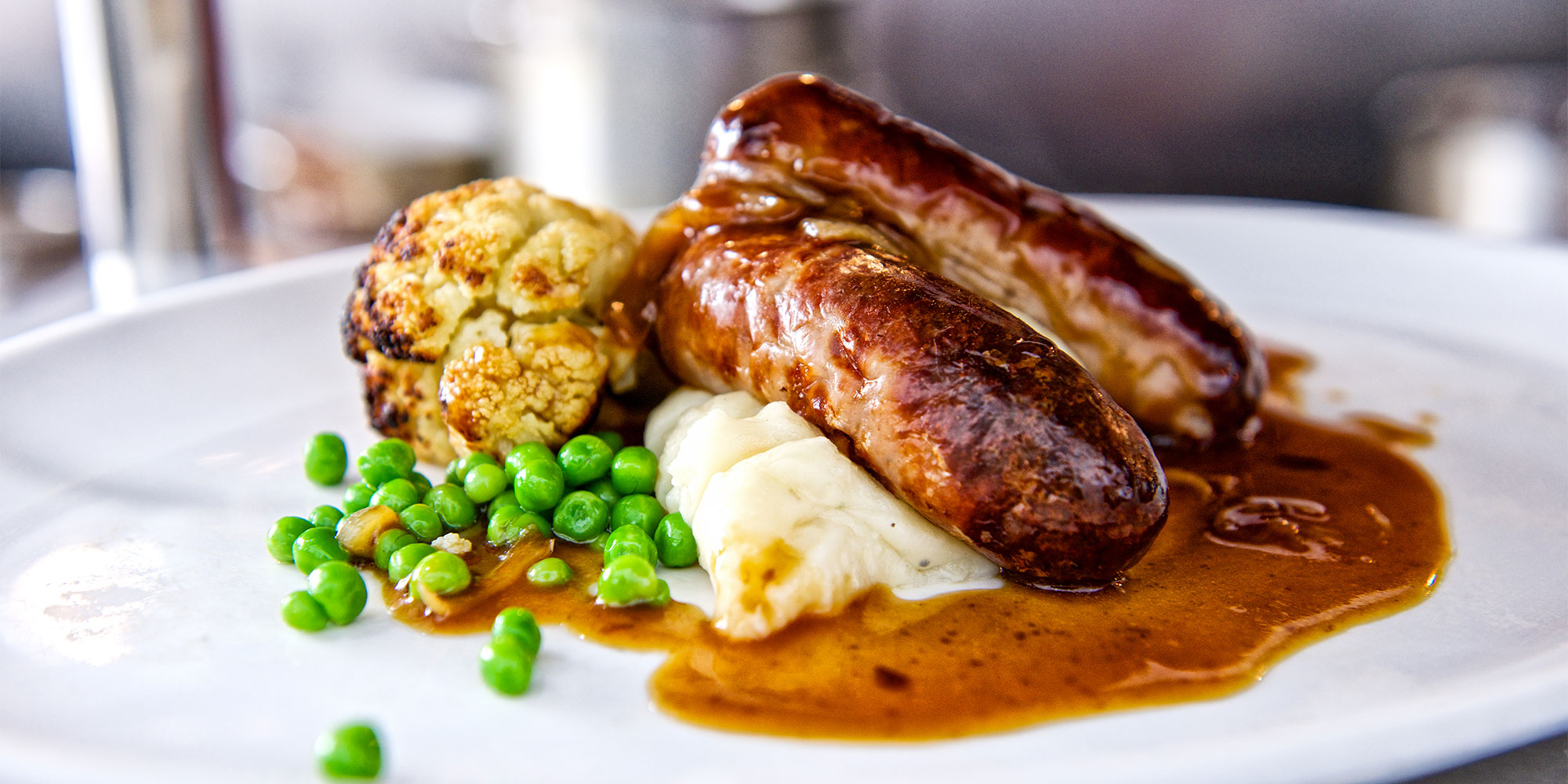 Sausages mash and peas on a dinner plate