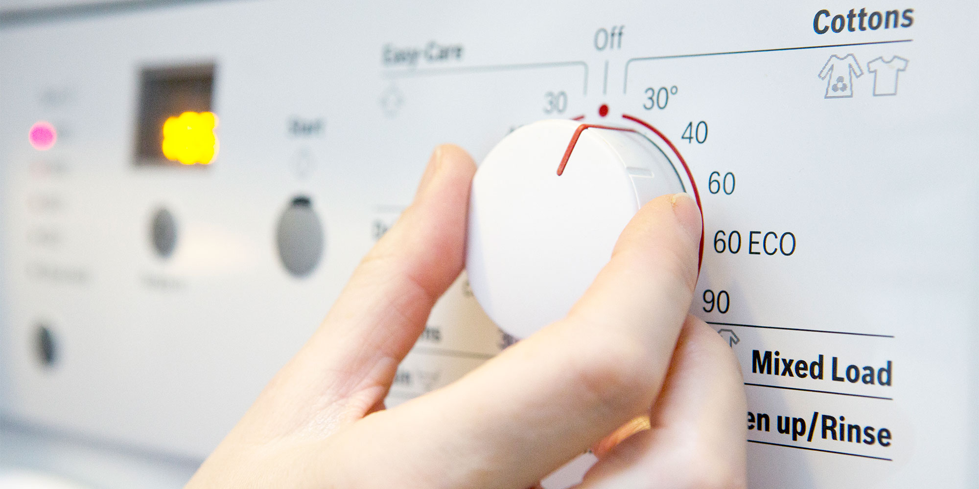 Hand turning temperature dial on washing machine