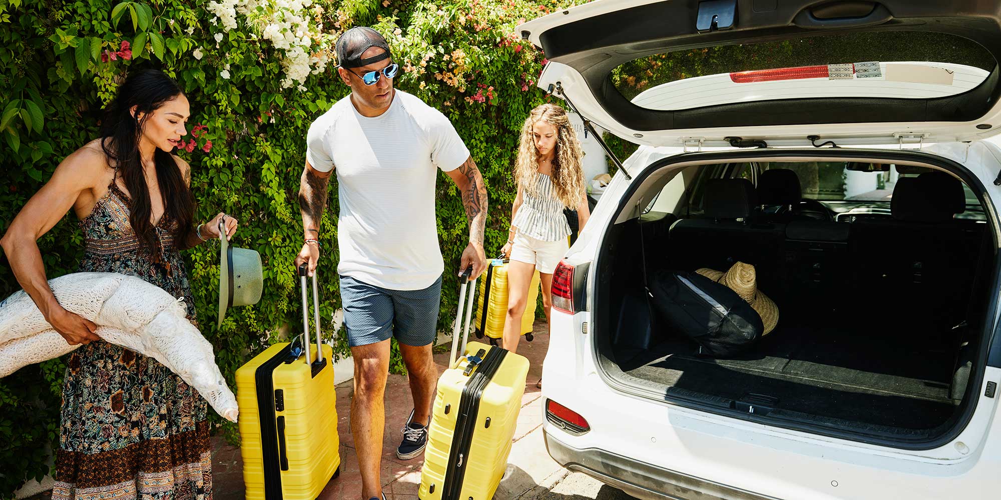 A family loading holiday luggage into the back of their car.