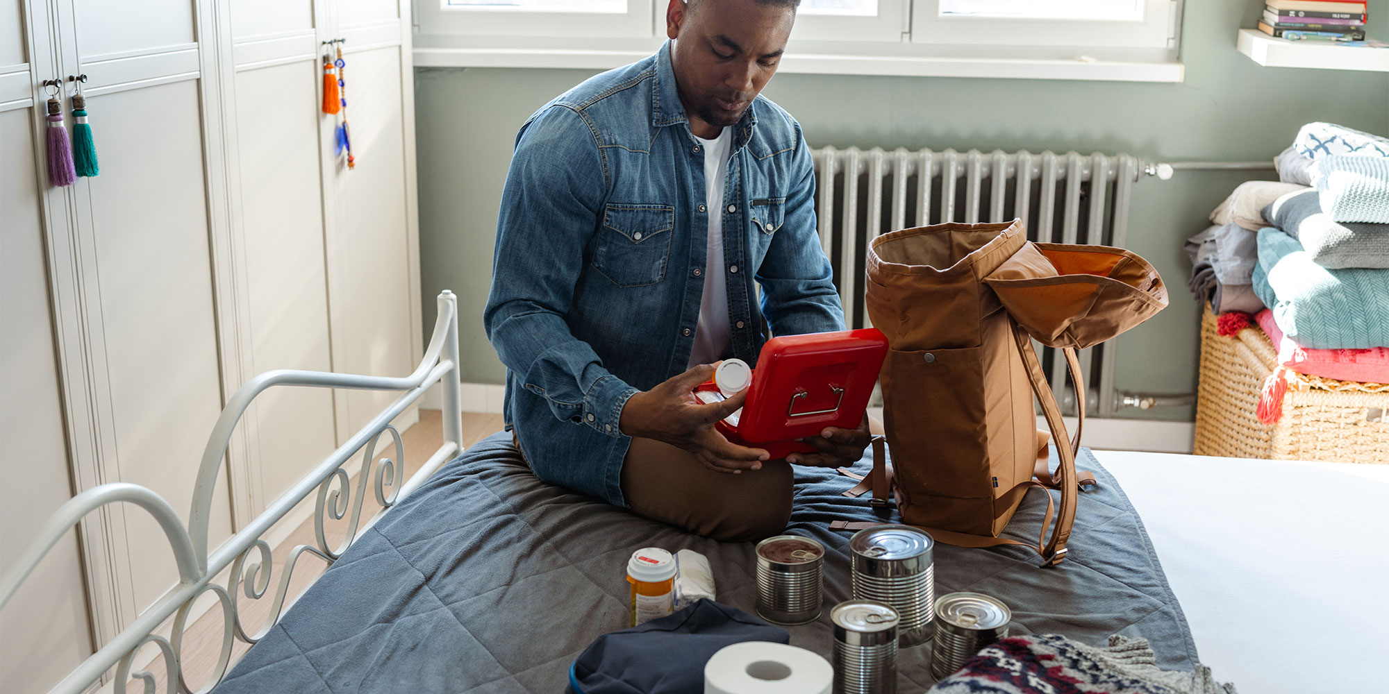 A man packing an emergency kit on a bed