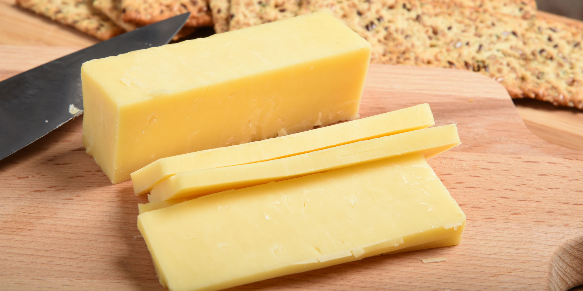 Close up of cheese slices on board with crackers