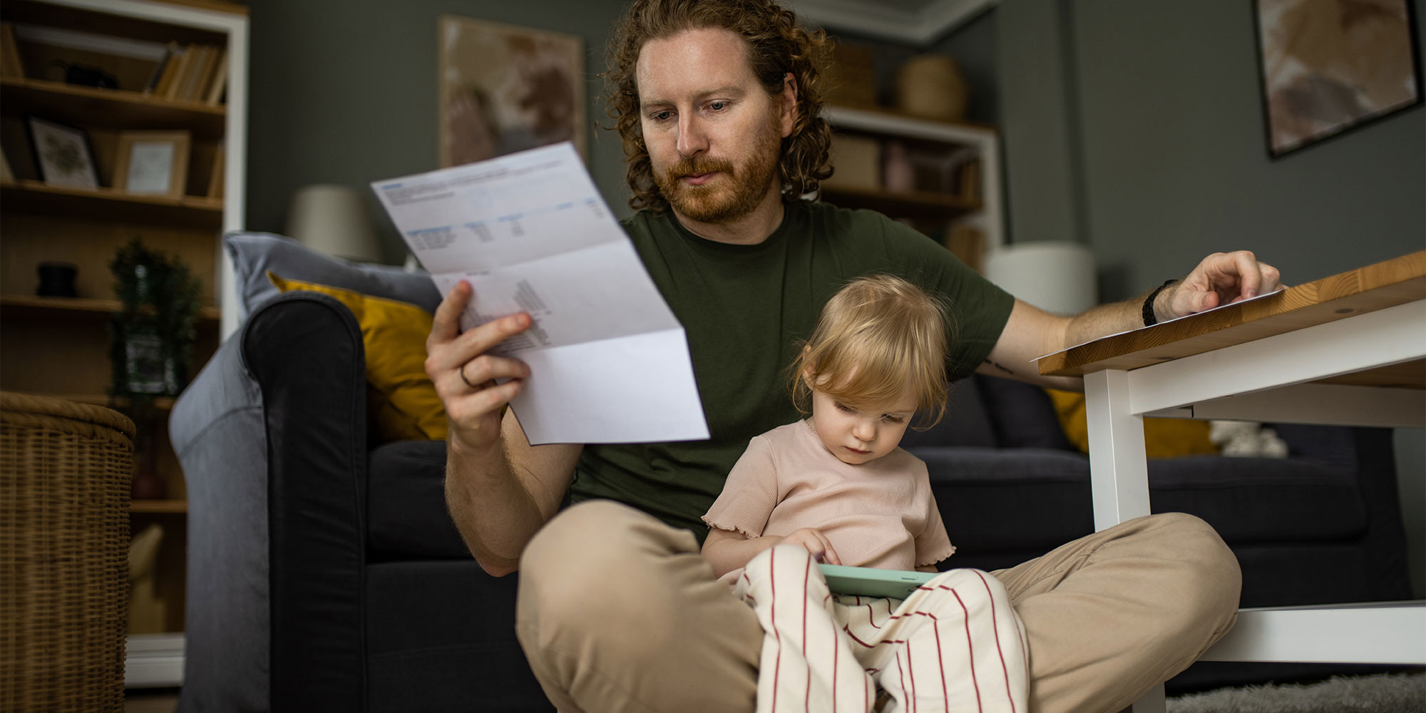 A father sits with his child while looking at a bill