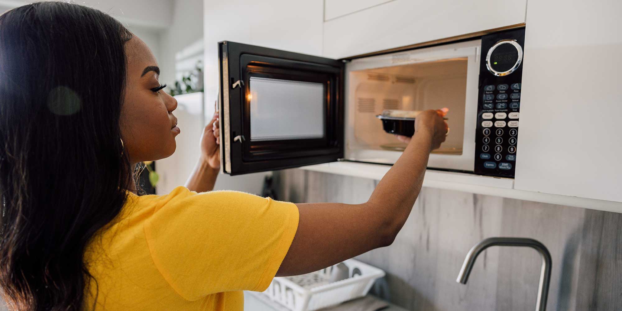 A person reheating leftover food in the microwave