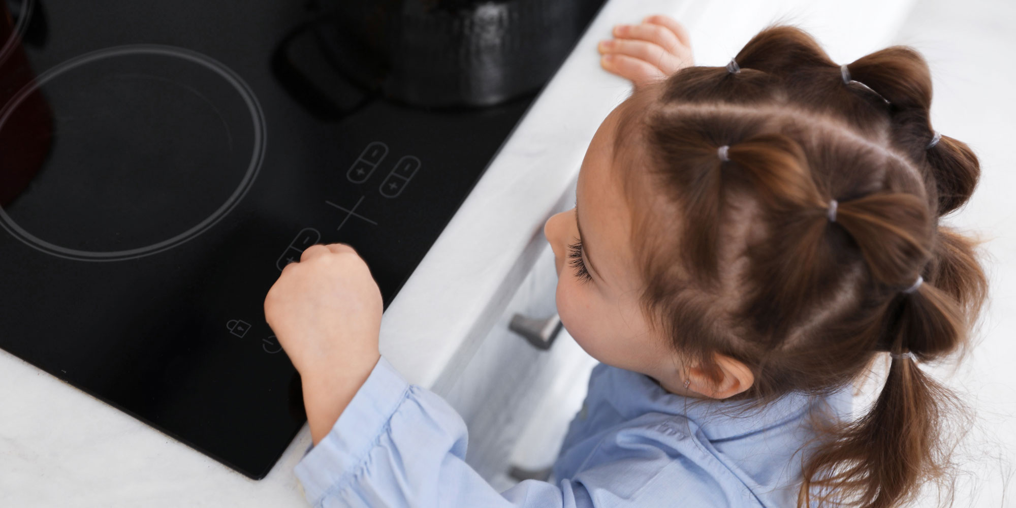 Child playing with induction hob controls