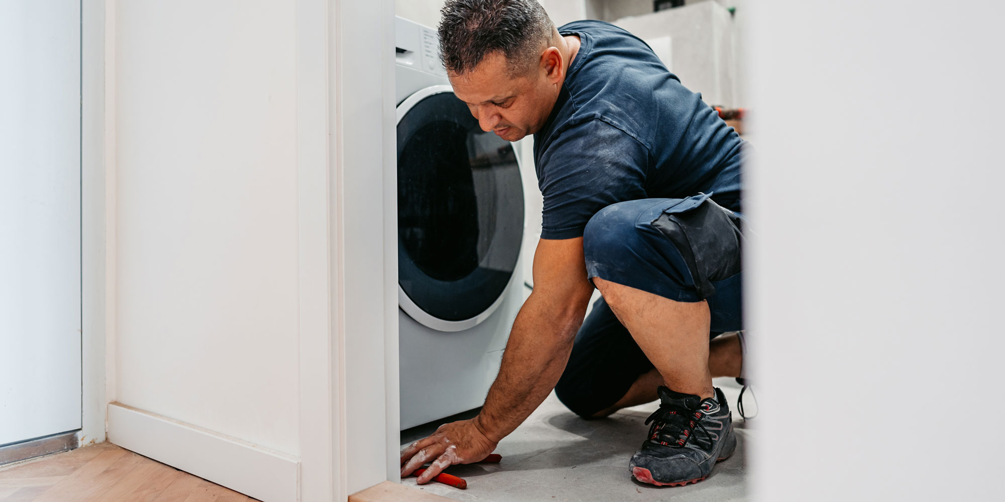 How to kit out your home - man installing washing machine