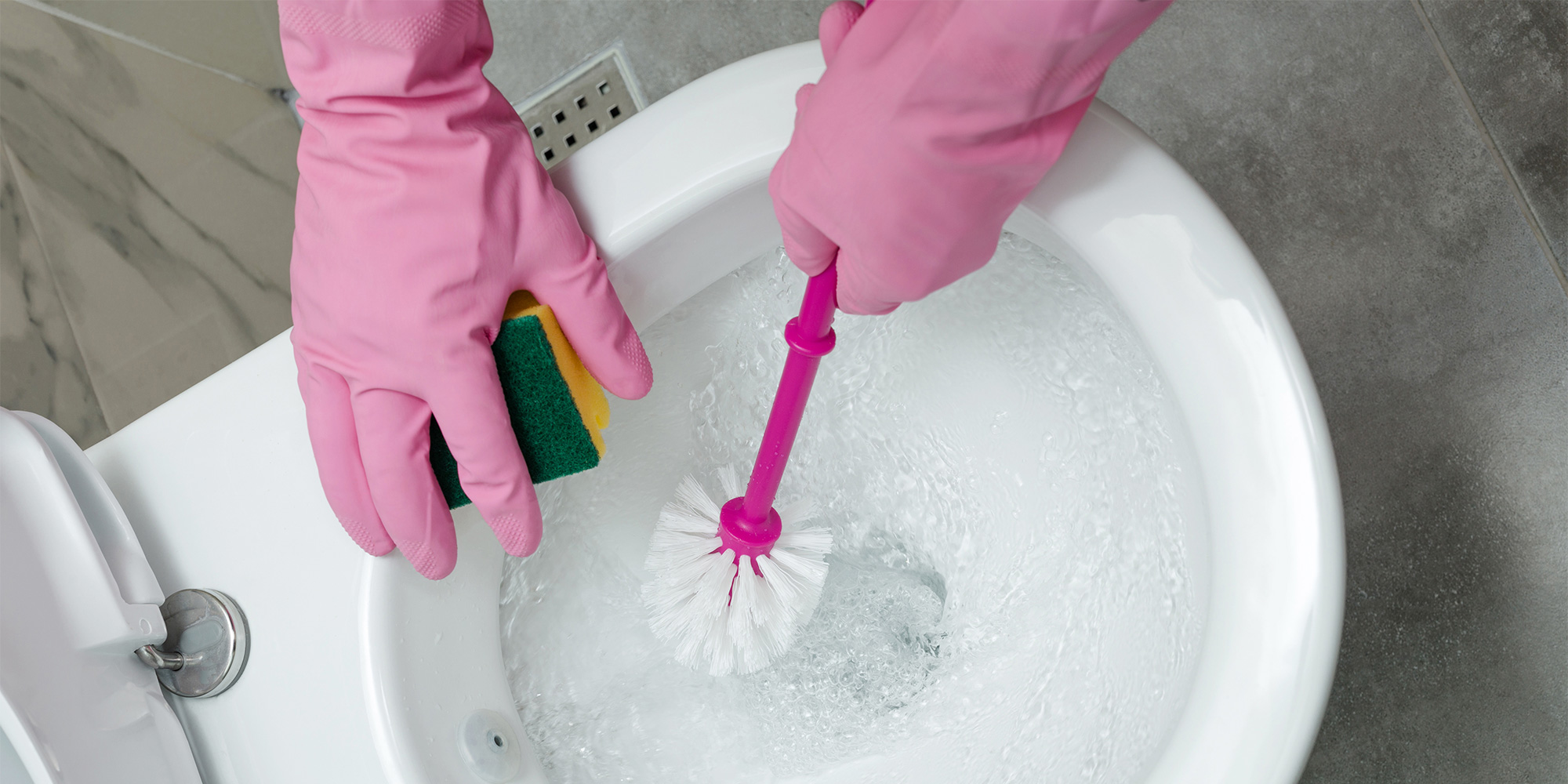 A toilet brush being rinsed in the flush of a toilet