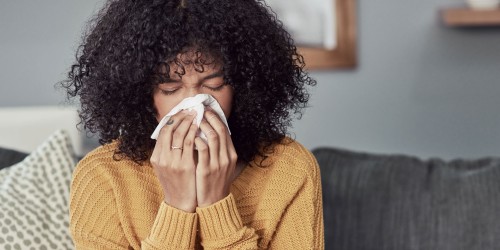 A person with a cold blowing their nose