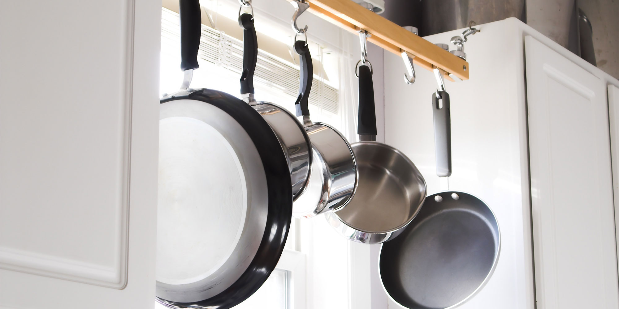 Five pans hanging up in a kitchen