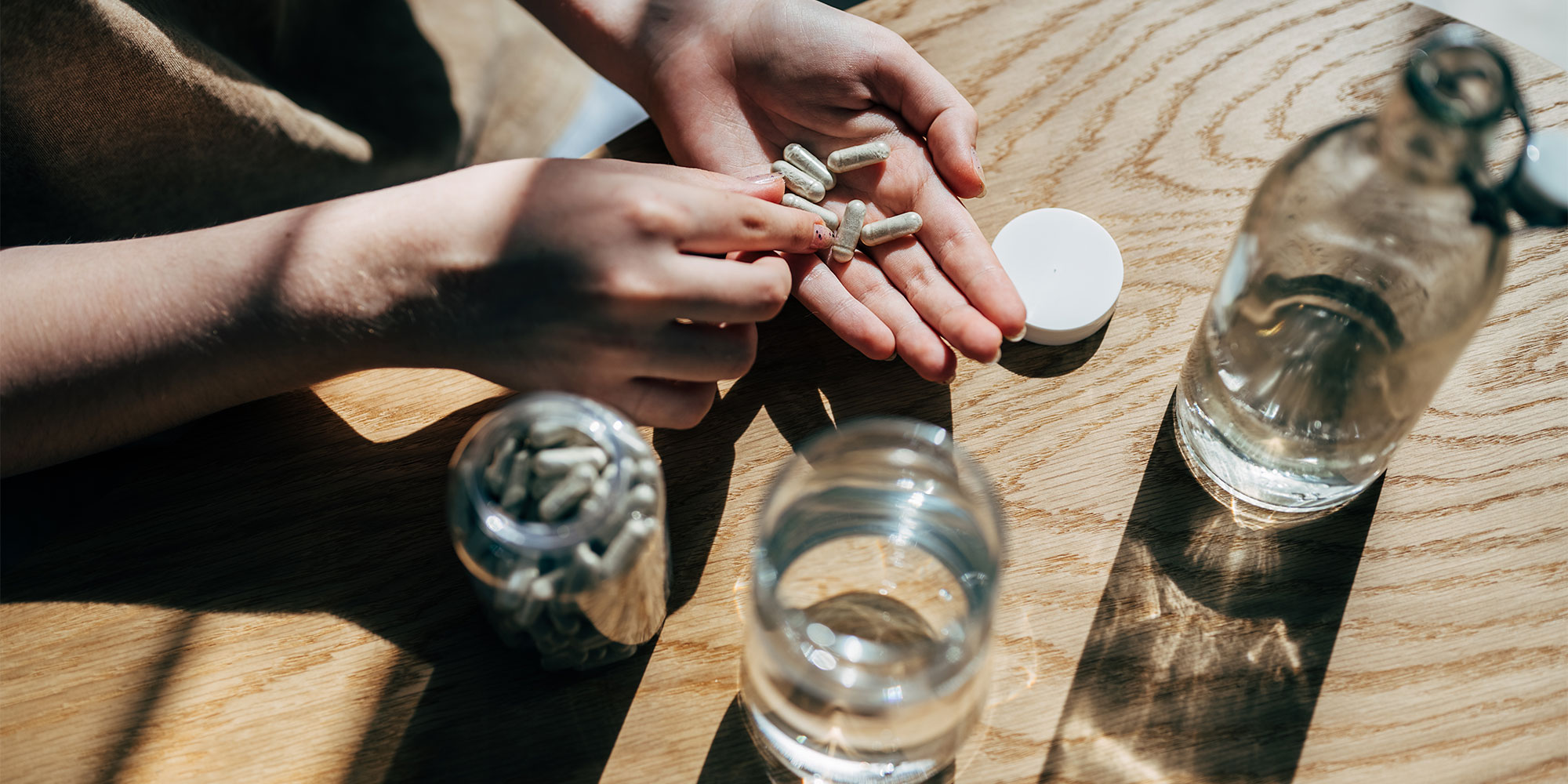 A view from above of hand taking a vitamin supplement