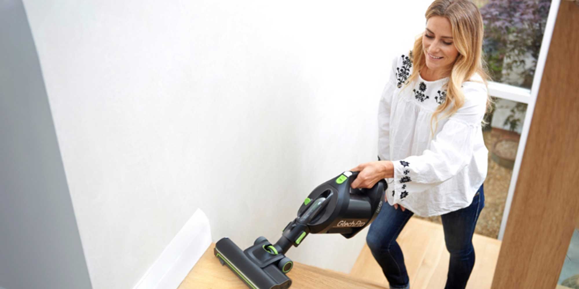 woman hoovering stairs with a gtech handheld vacuum