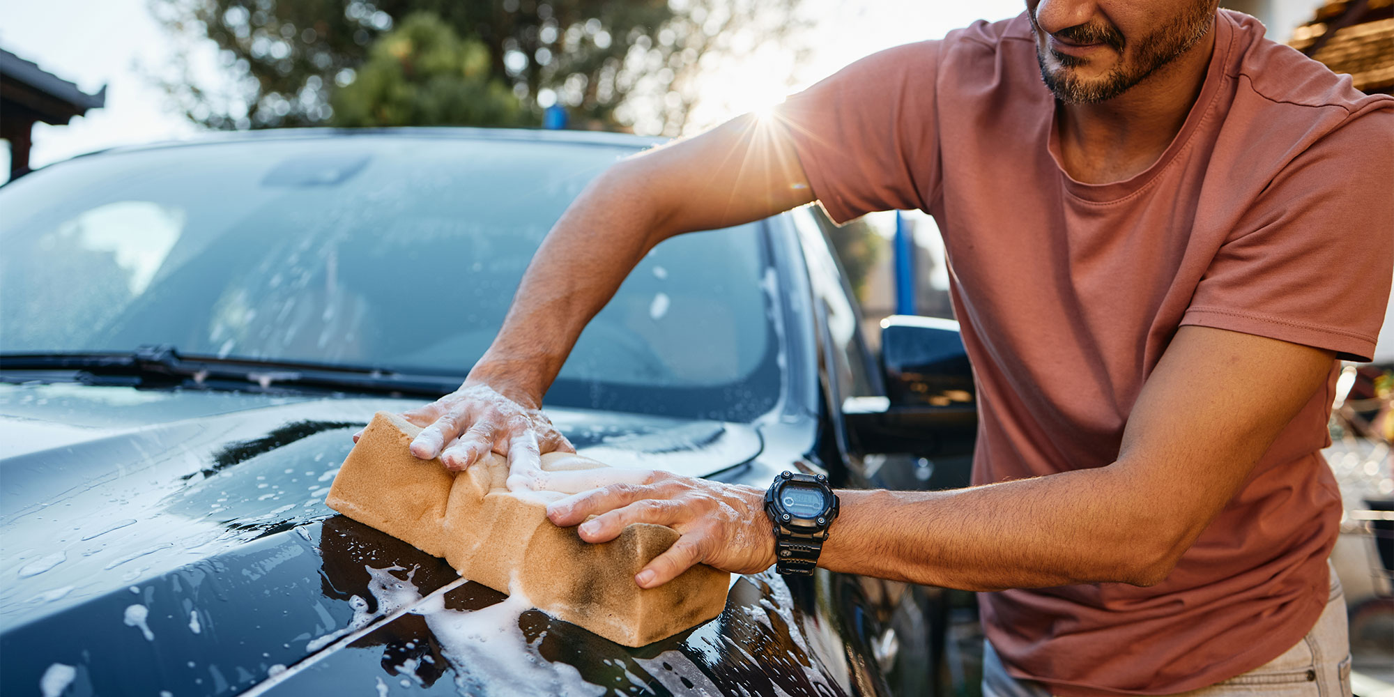 A man using a sponge to clean the car