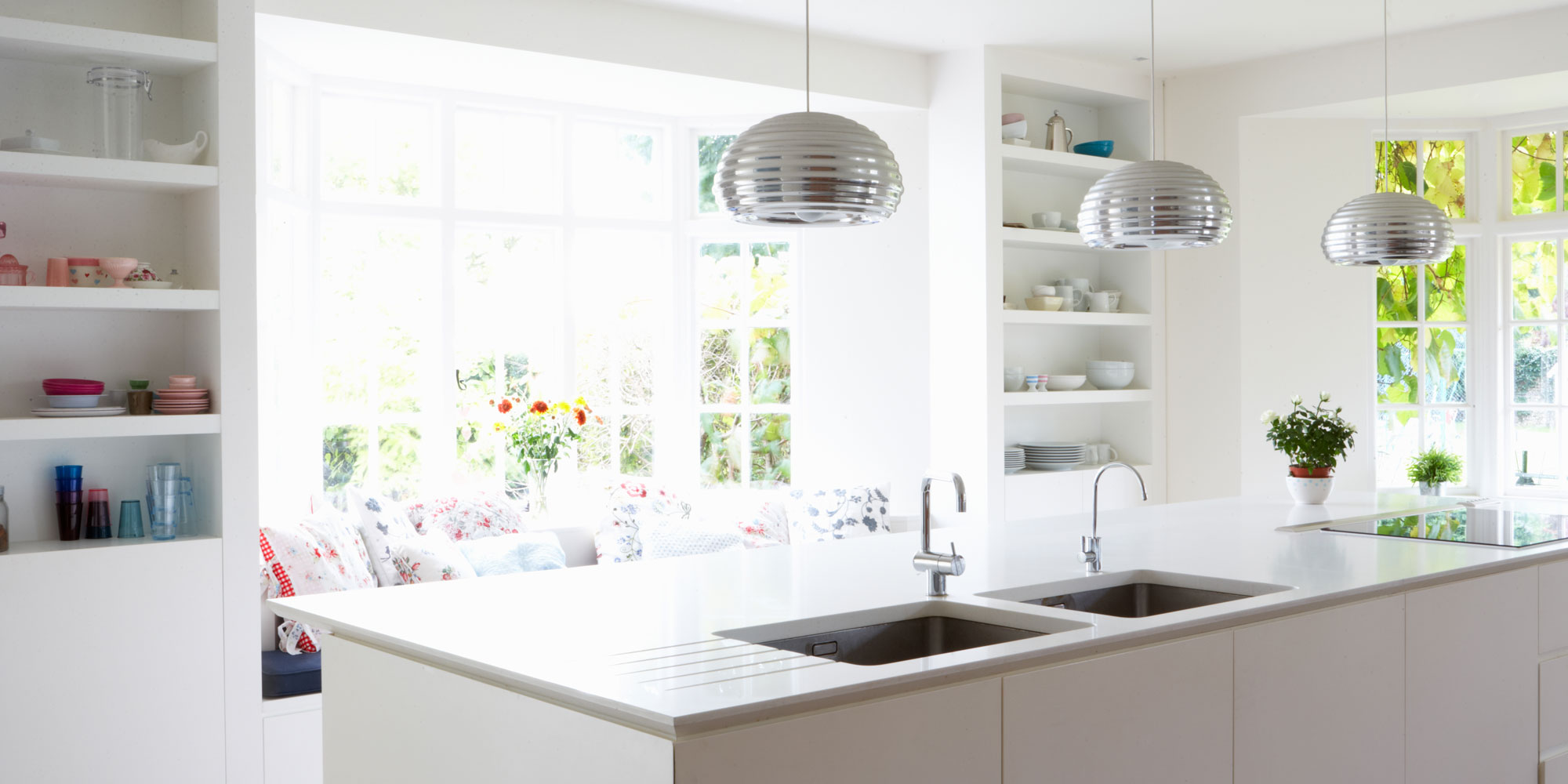Neutral cream kitchen with island. Above the island, two large stainless steel lights