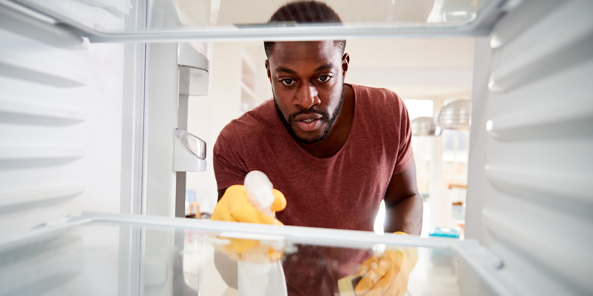A man cleaning a fridge shelf