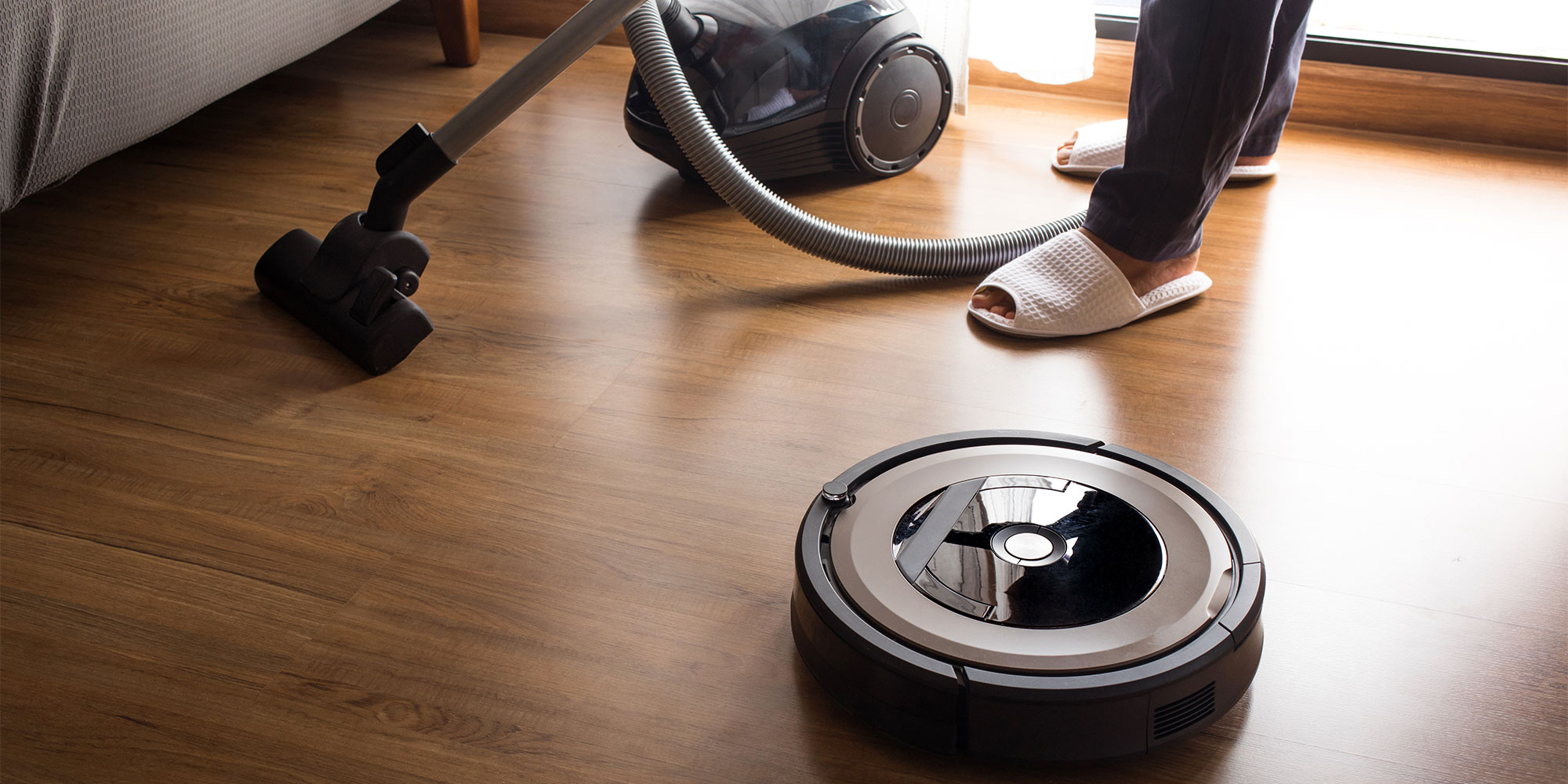 A robot vacuum next to a corded vac