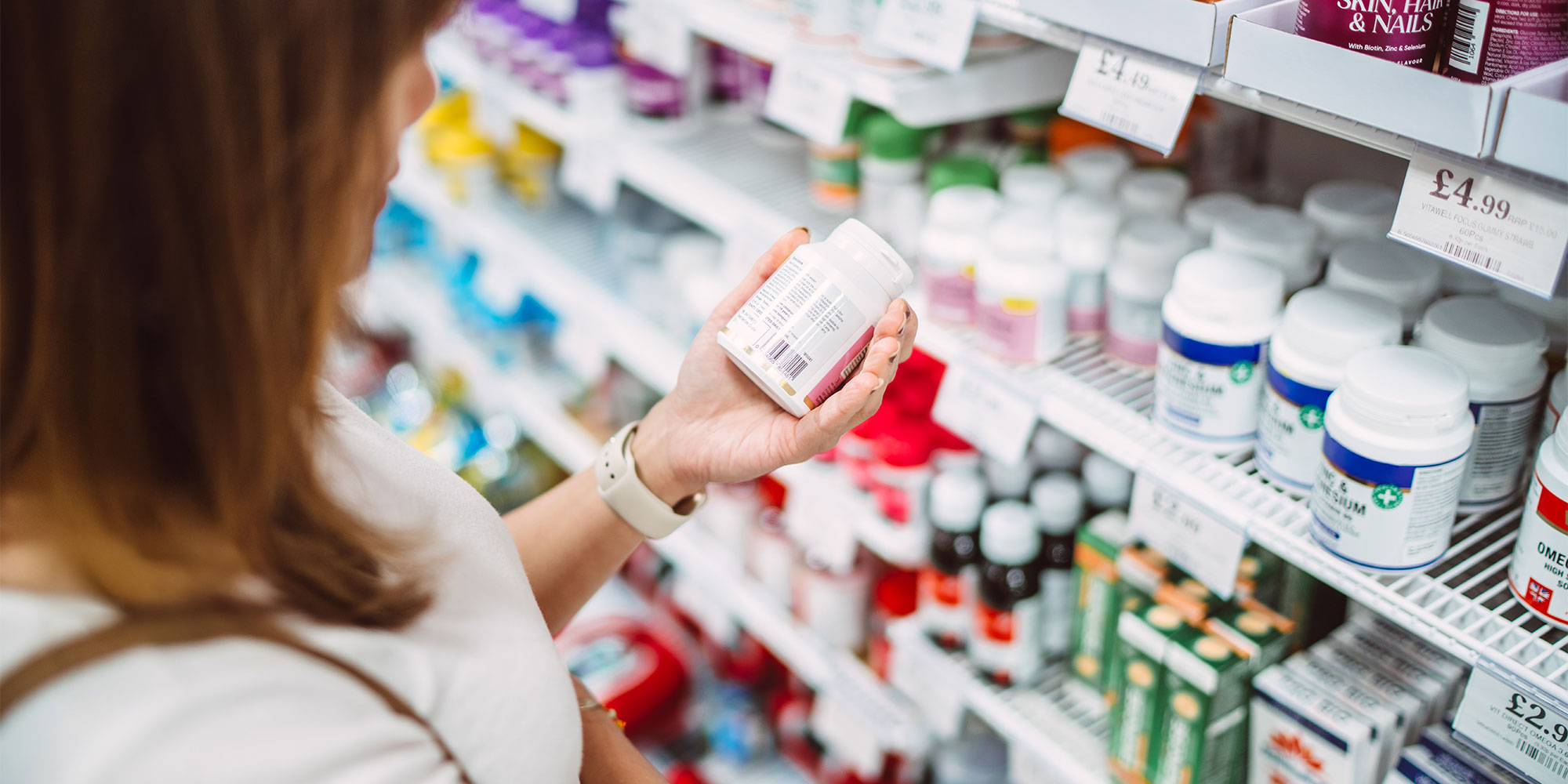 Woman scanning a supplement bottle from a supermarket shelf