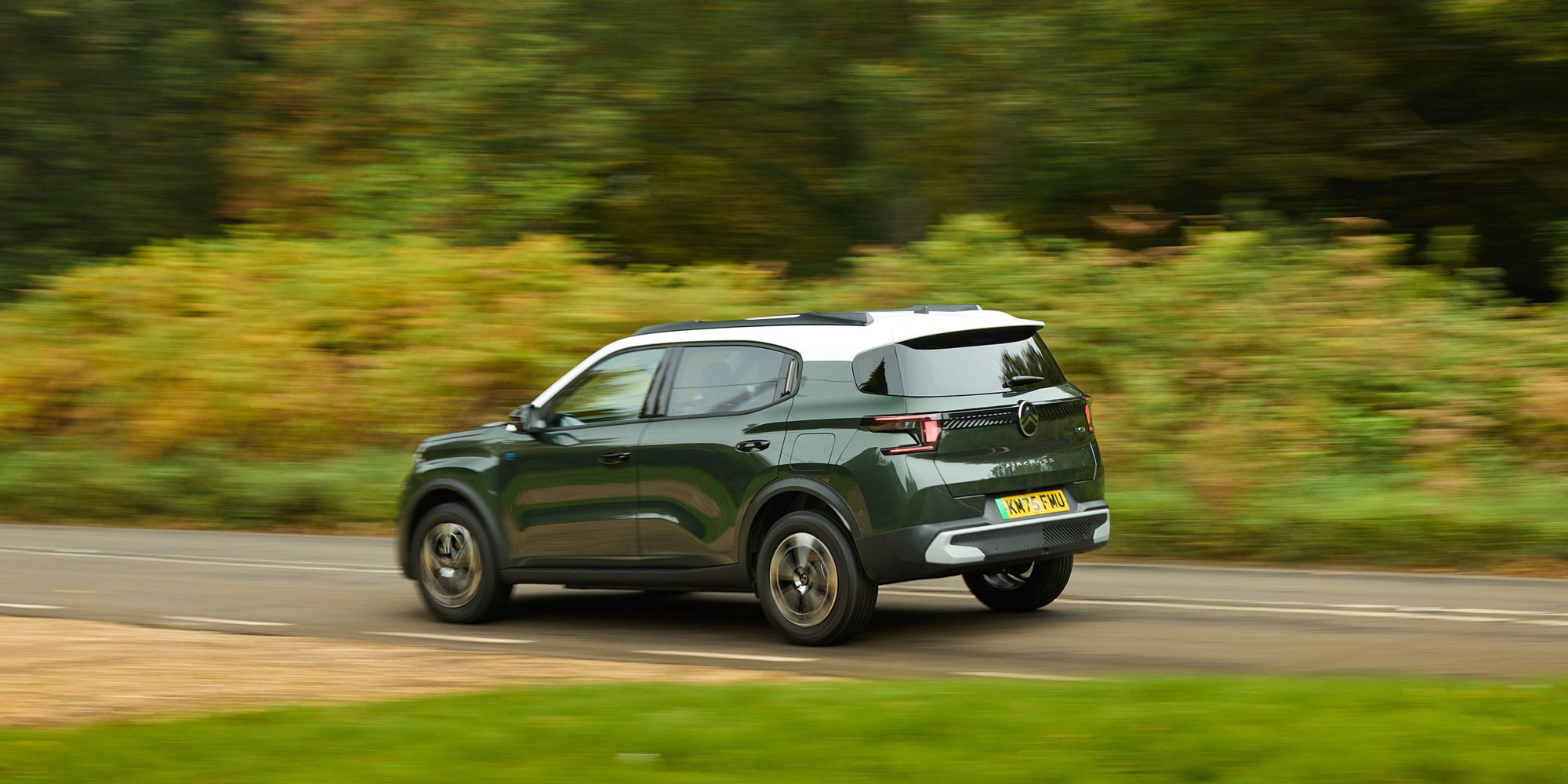 A green and white Citroen e-C3 Aircross being driven on a UK road