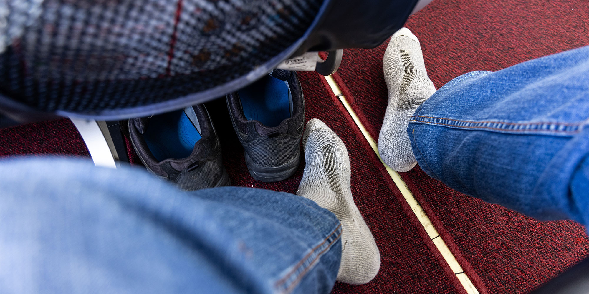 Person in jeans and socks, on a red carpet on an aeroplane