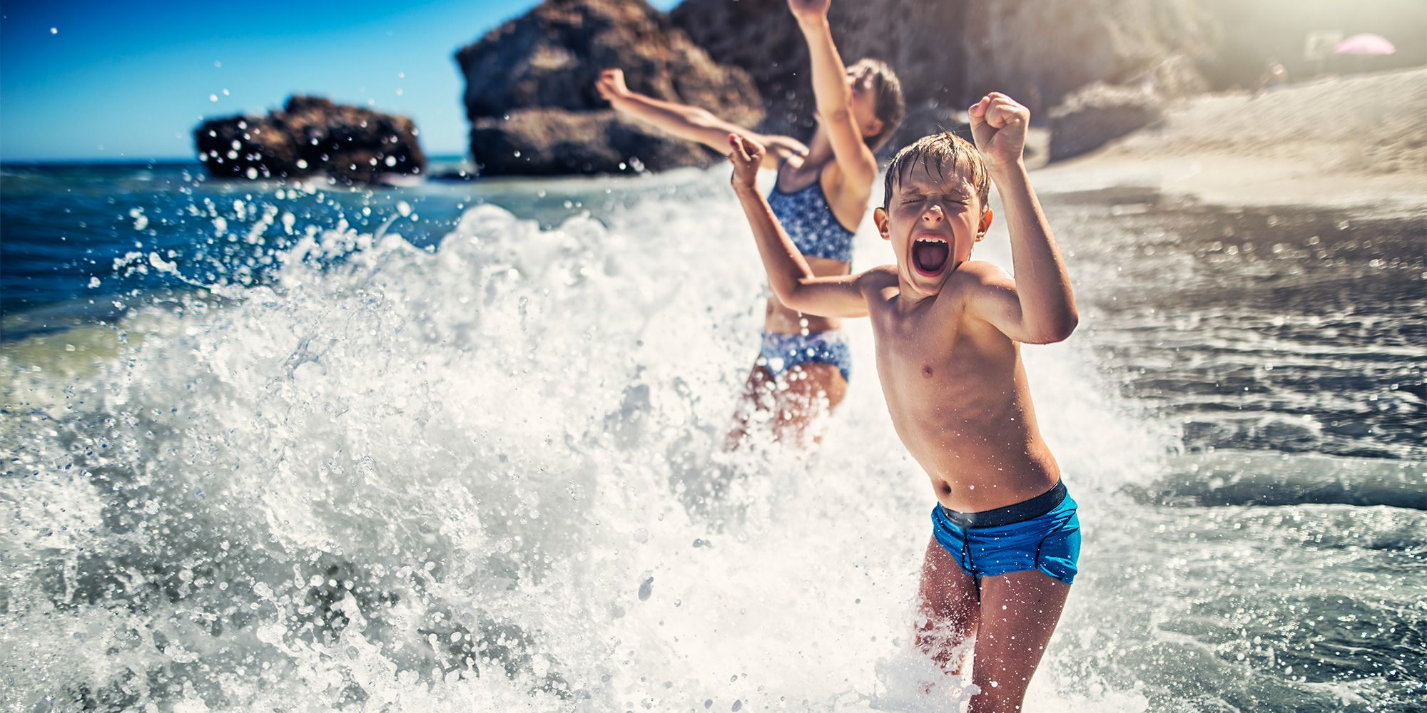children splashing in the sea at the beach