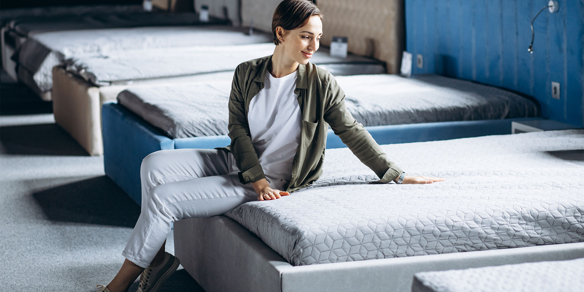 Woman sitting on a mattress in a bed shop