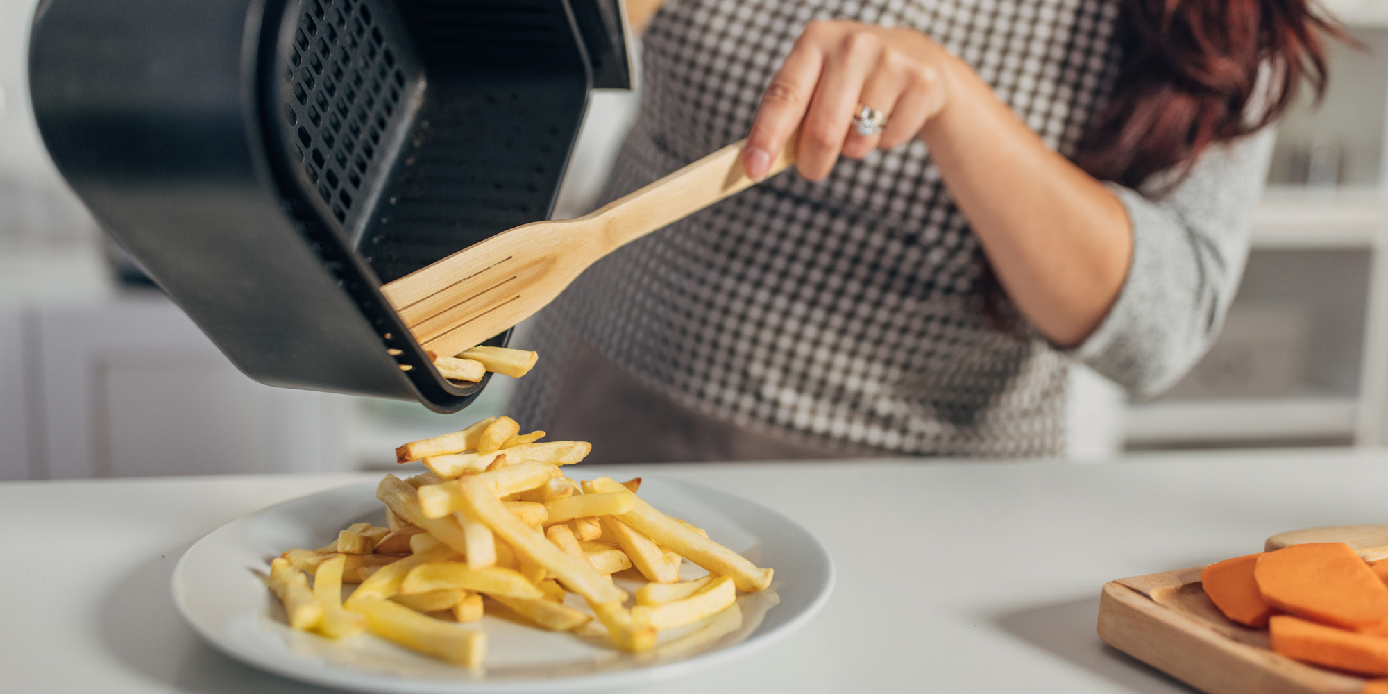 A person removing chips from the air fryer