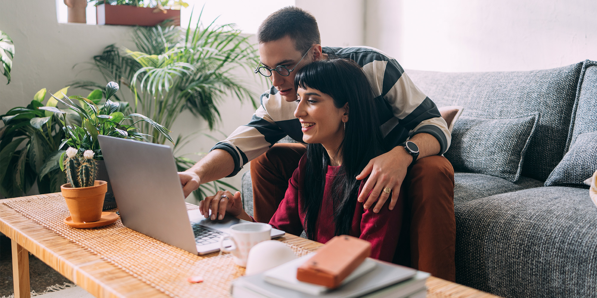 Couple look at a laptop placed on a coffee table while booking a holiday