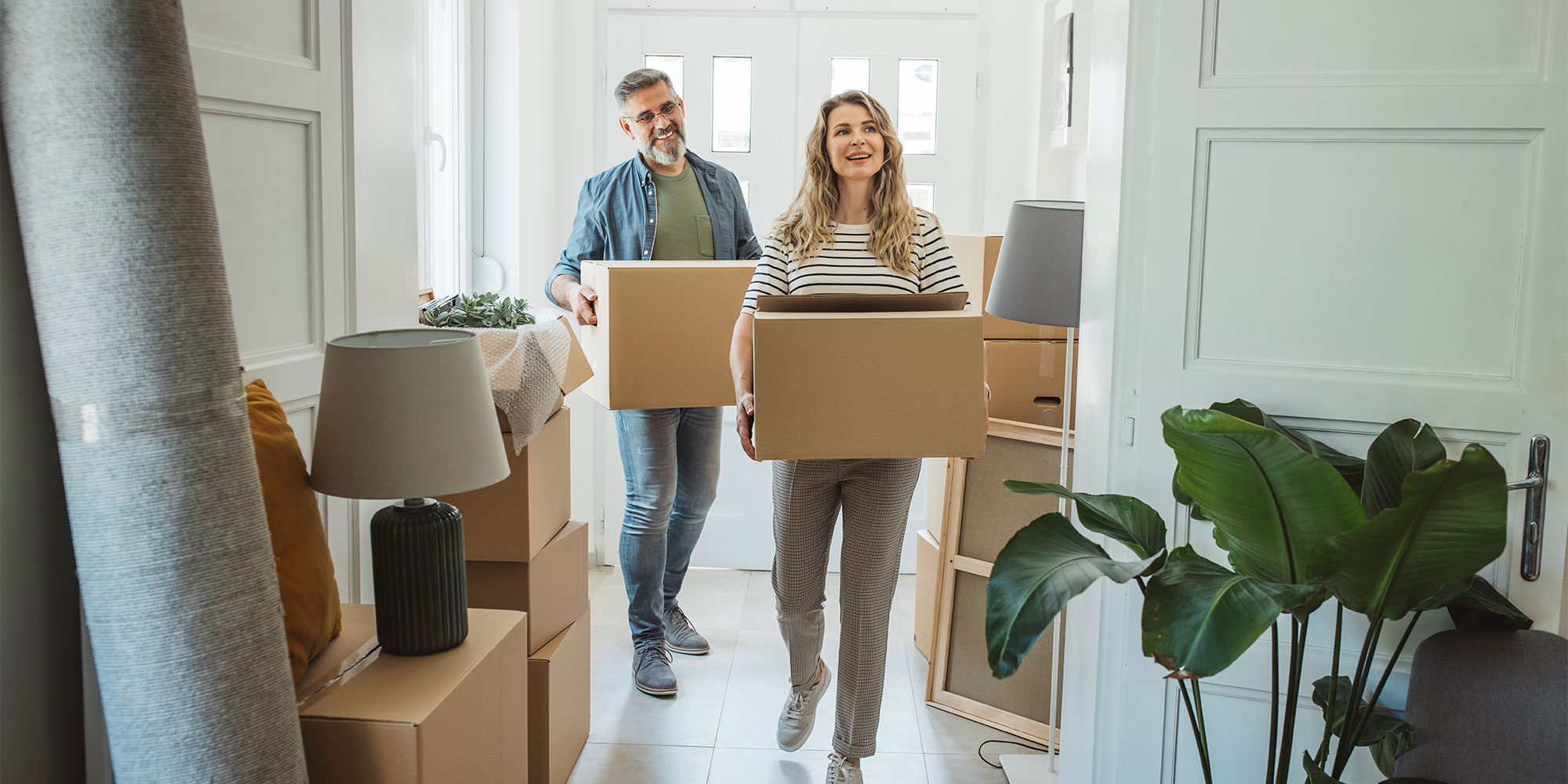 A couple carrying boxes into their new home
