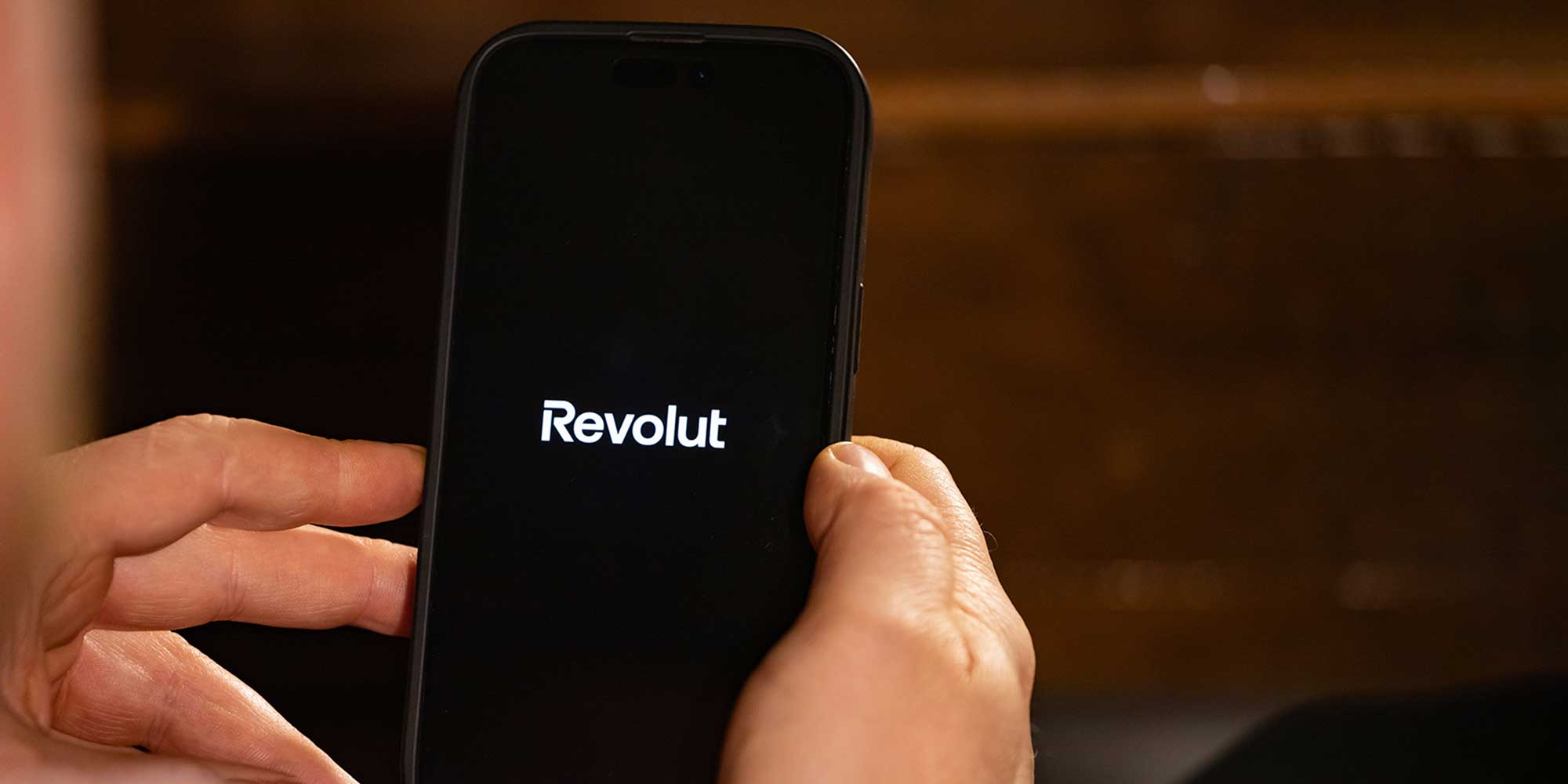 Hand holding mobile phone showing Revolut logo