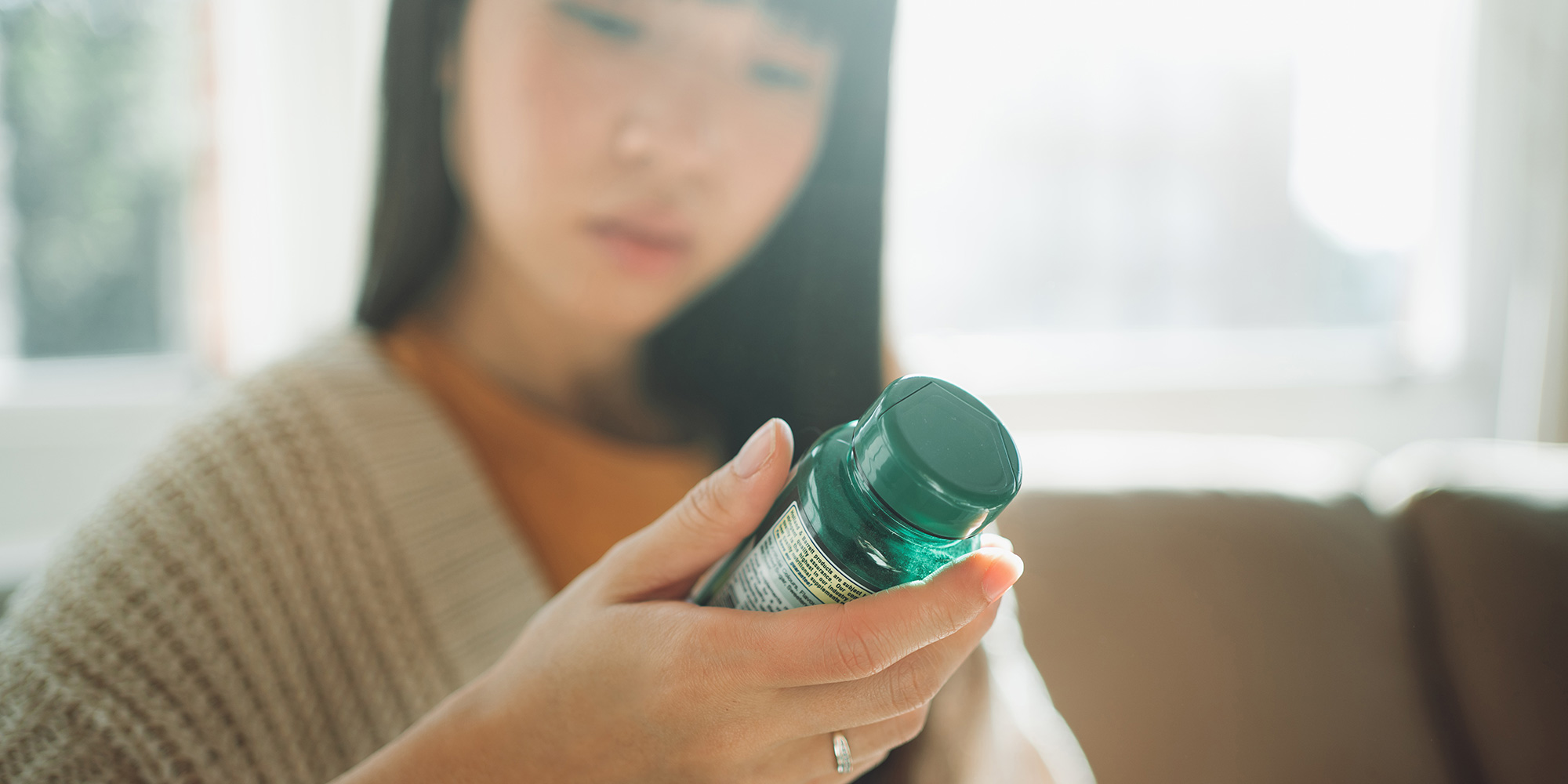 Woman examining the label on a bottle of pills or supplements