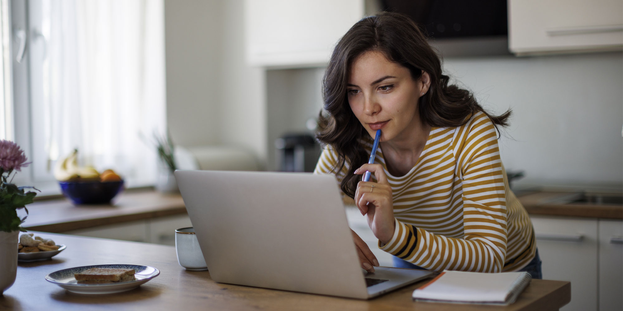 a woman looking thoughtfully at a laptop