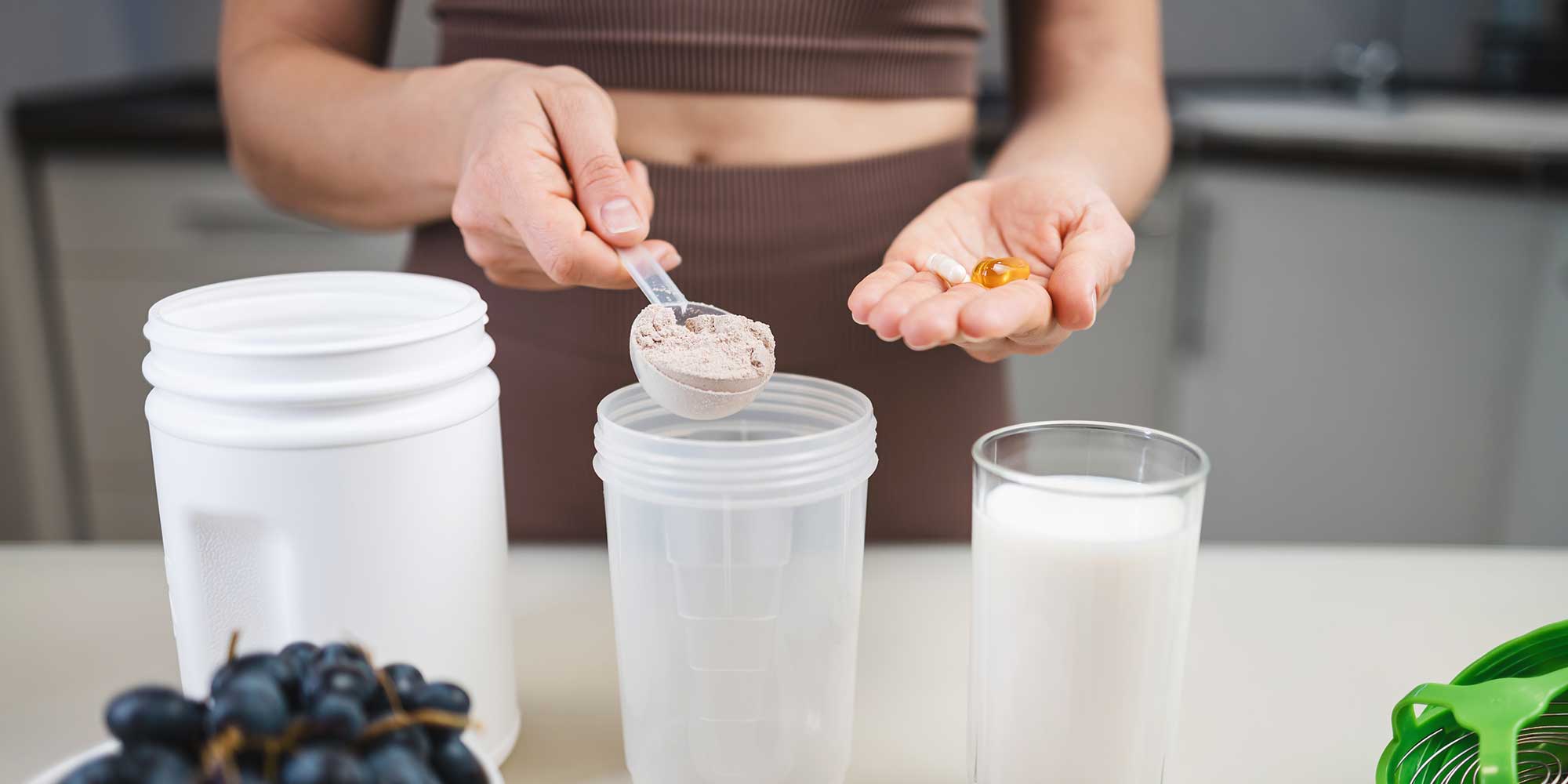 Someone measuring out a spoon of powder into a smoothie