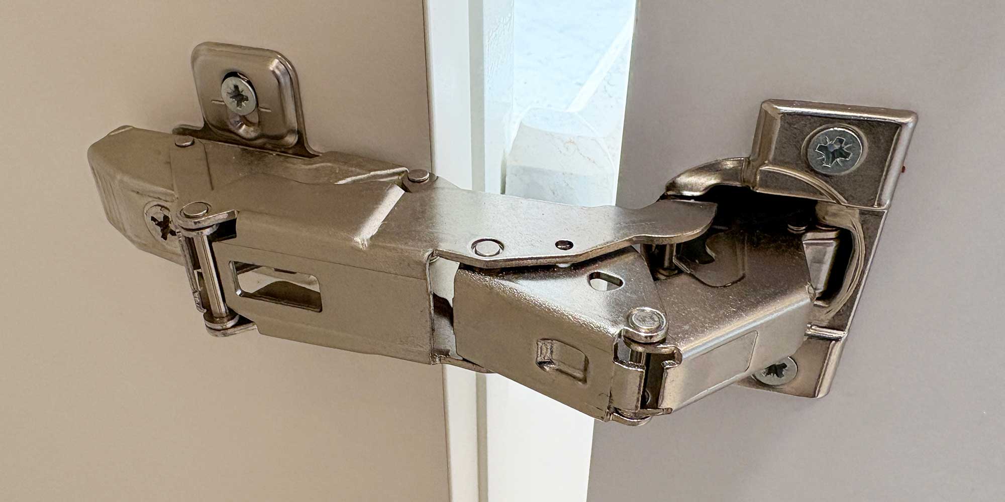 A silver door hinge on a white door.