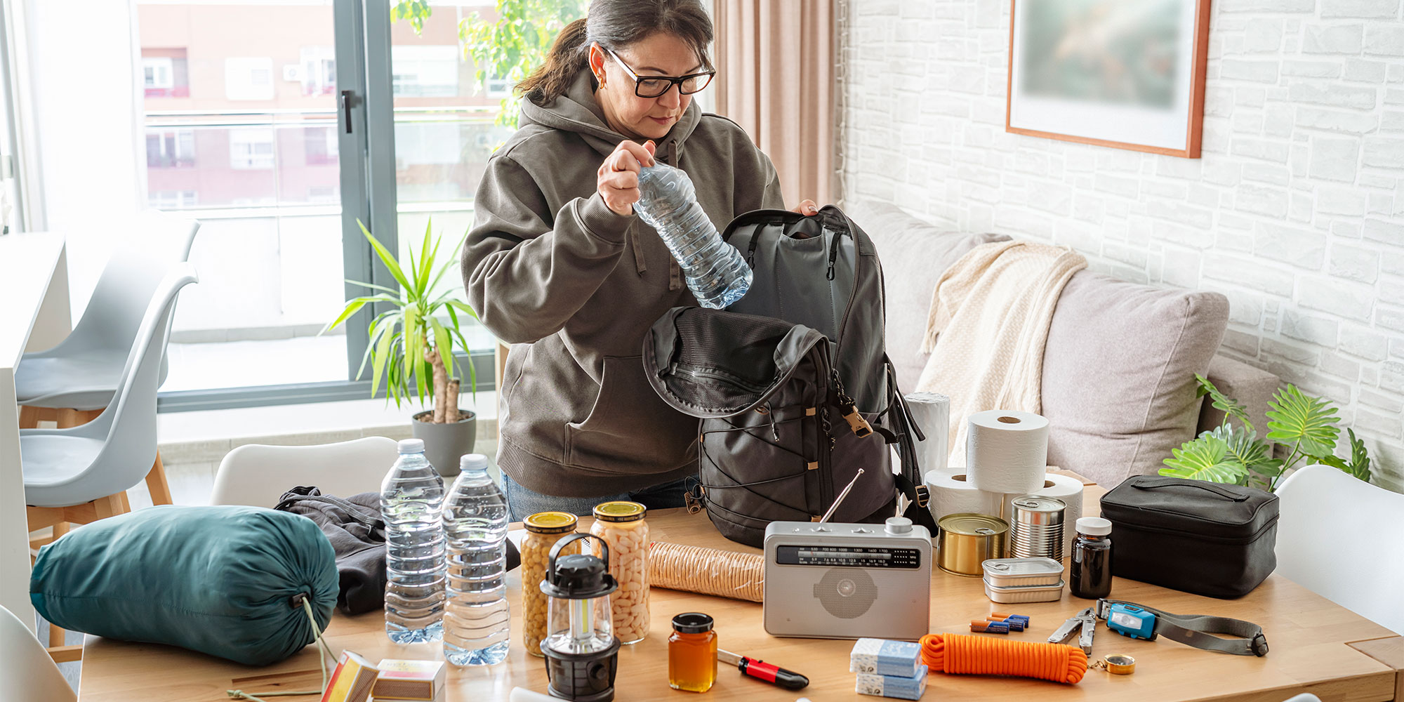A woman packing a bag with emergency supplies