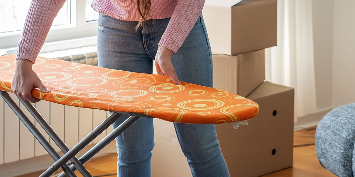 person pulling lever and closing an ironing board