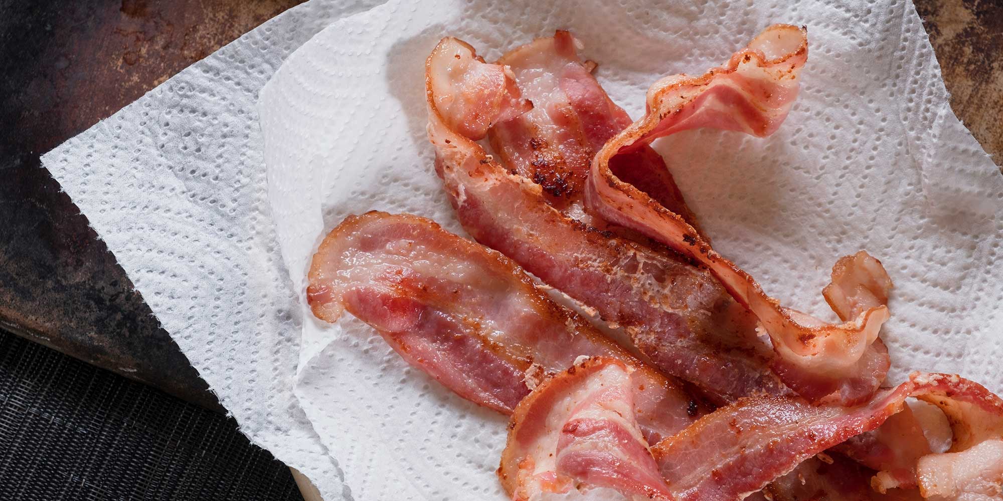 Cooked bacon lying on kitchen paper, which can be used to absorb some of the fat from cooking.