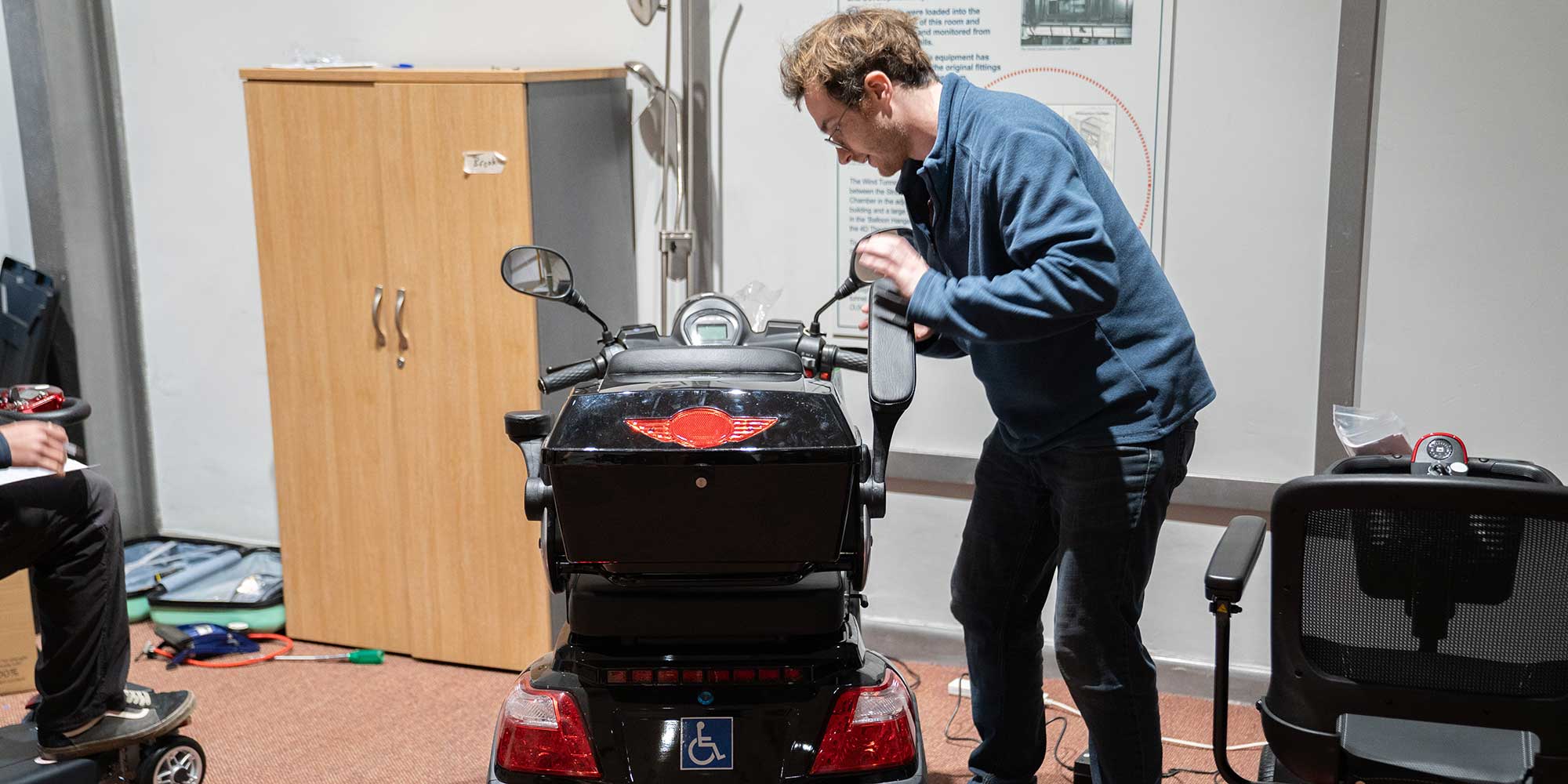 A tester adjusting the armrest of one of the mobility scooters