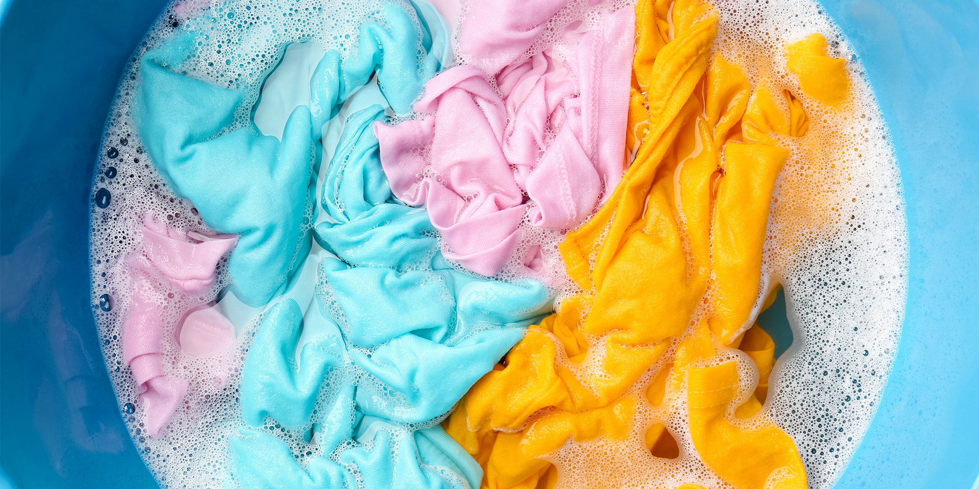 laundry being soaked in a bucket of soap and water