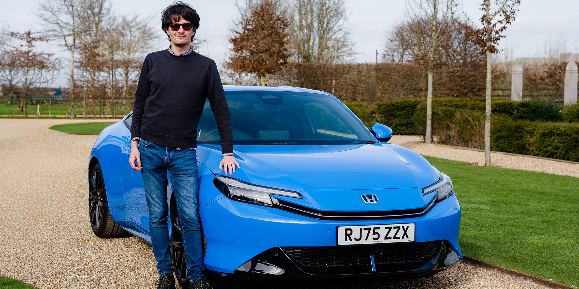 Dino Buratti stands next to a Honda Prelude, which is parked on gravel next to a lawn.