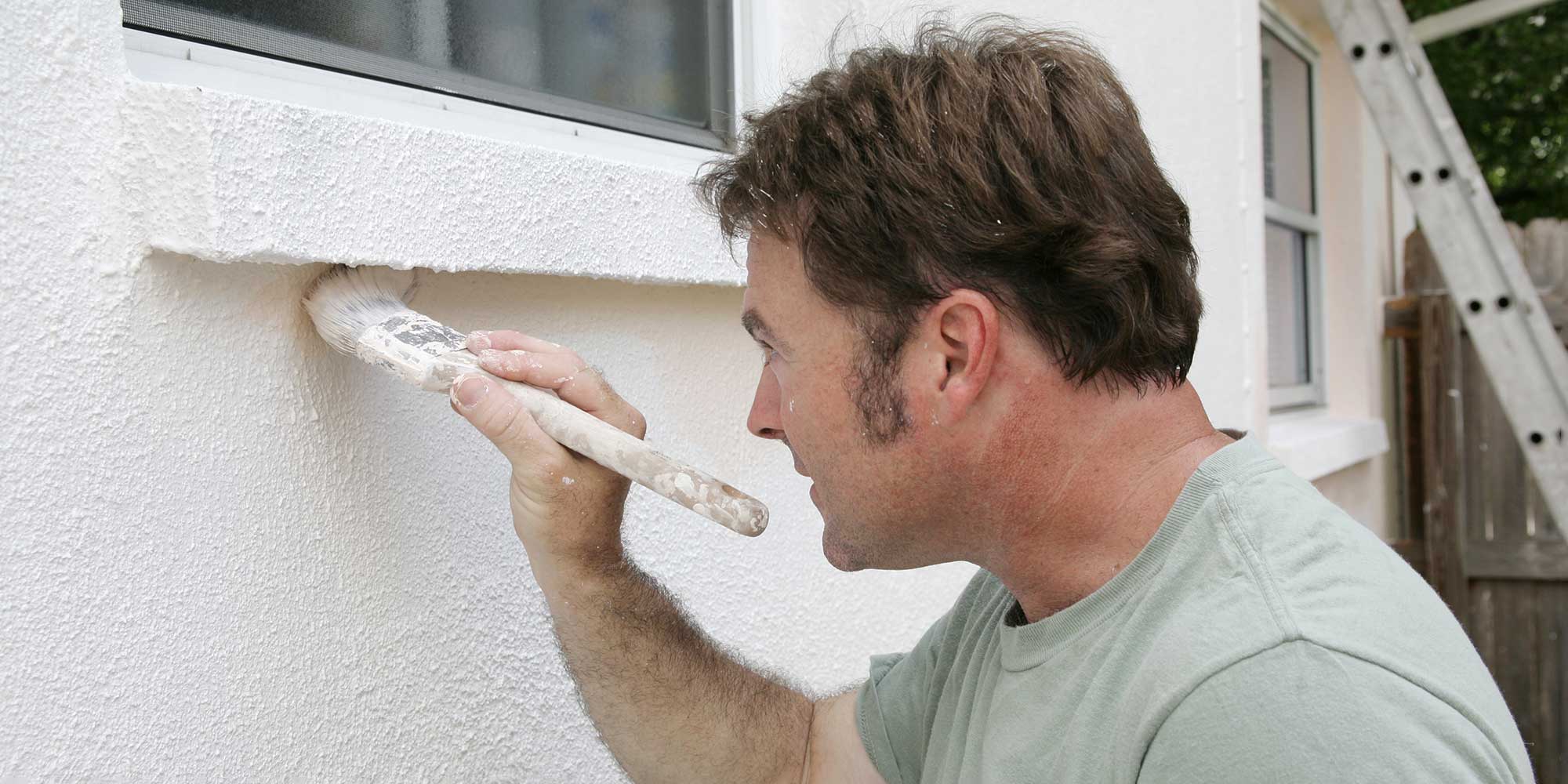 a man applying dampproof paint to an external wall