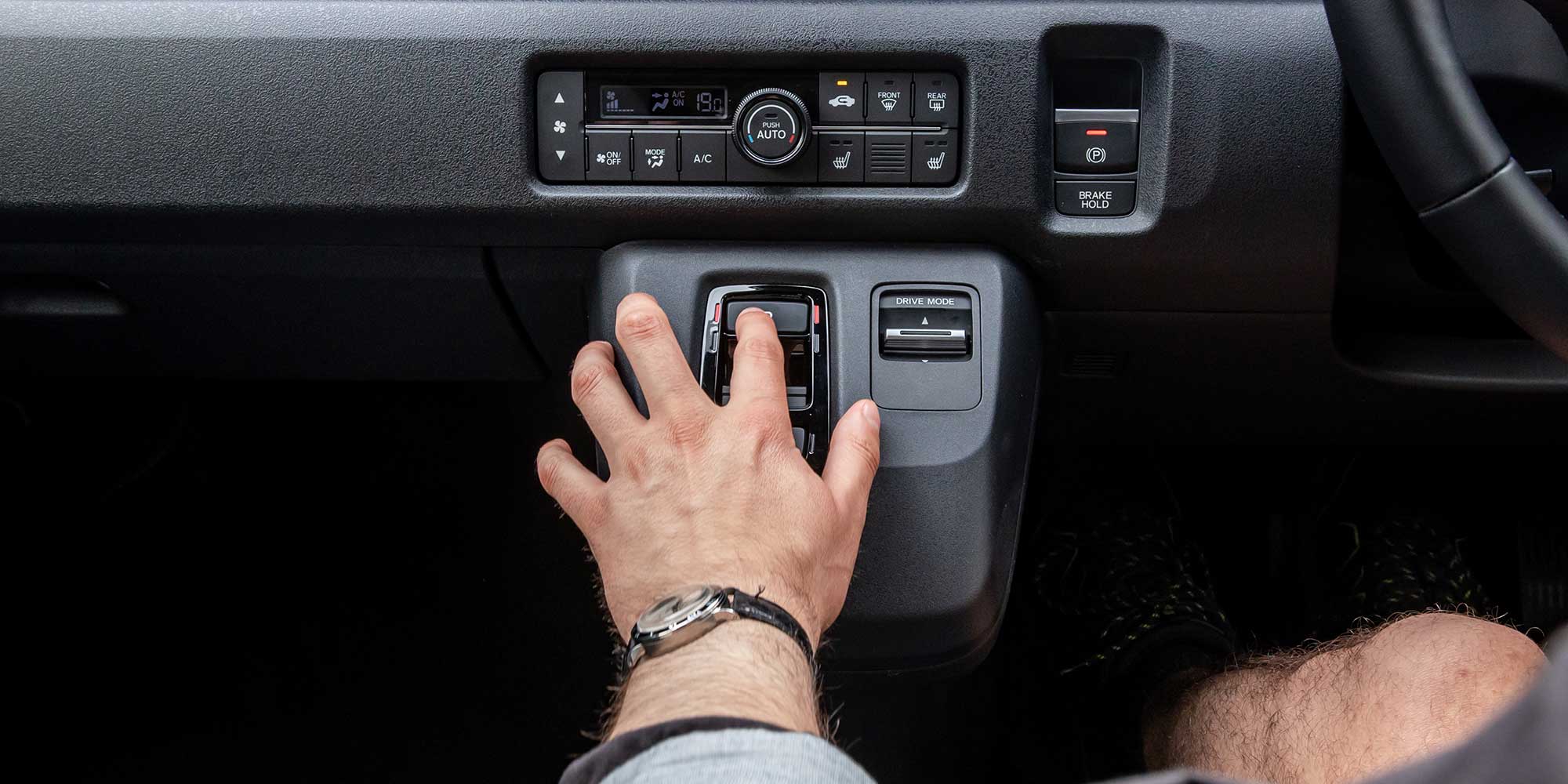 A person's hand is pressing a button on the Honda Super-N's centre console