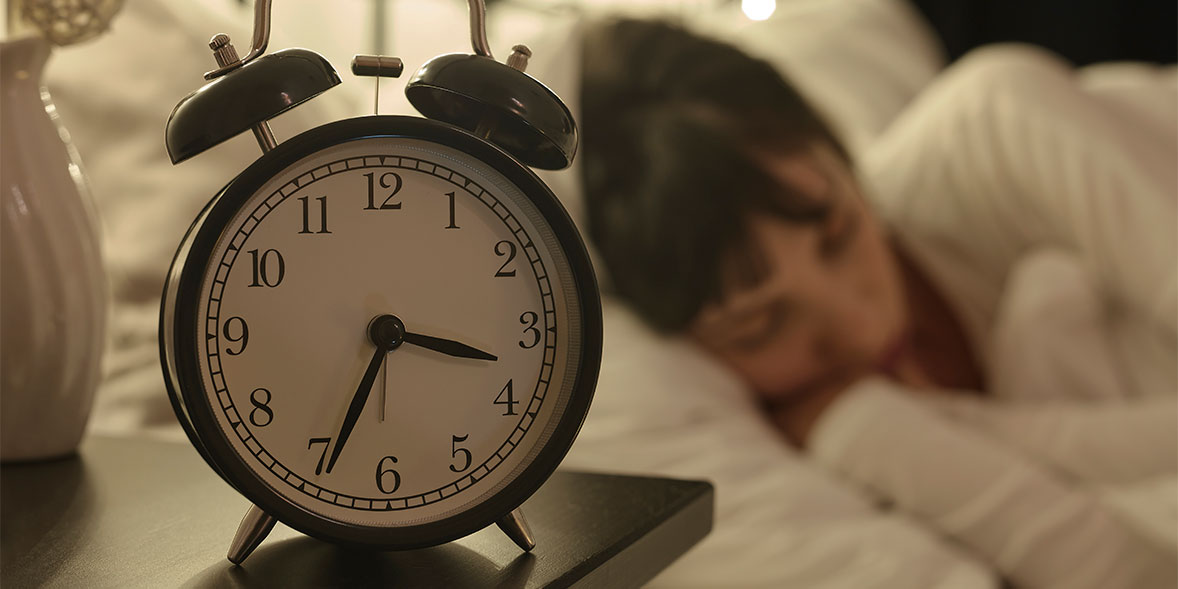 Woman sleeping next to an alarm clock