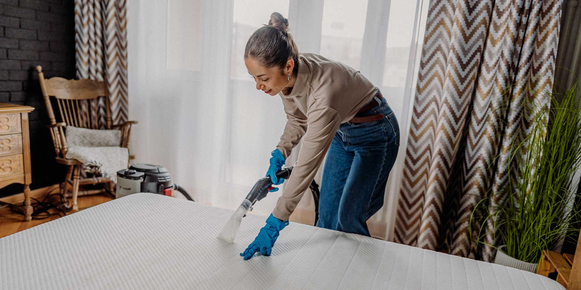 A woman wearing blue gloves and cleaning a mattress